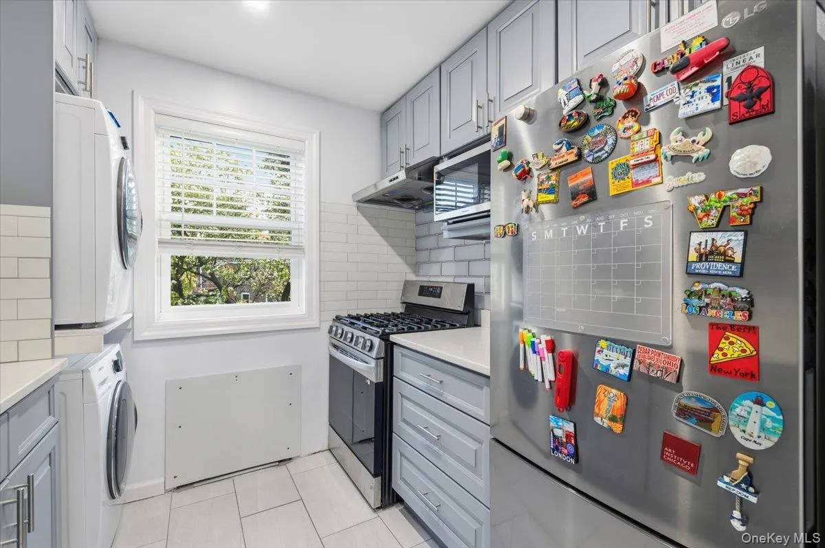 Kitchen featuring light gray cabinetry, white subway tile backsplash, and light-toned tile flooring Kitchen featuring light gray cabinetry, white subway tile backsplash, and light-toned tile flooring