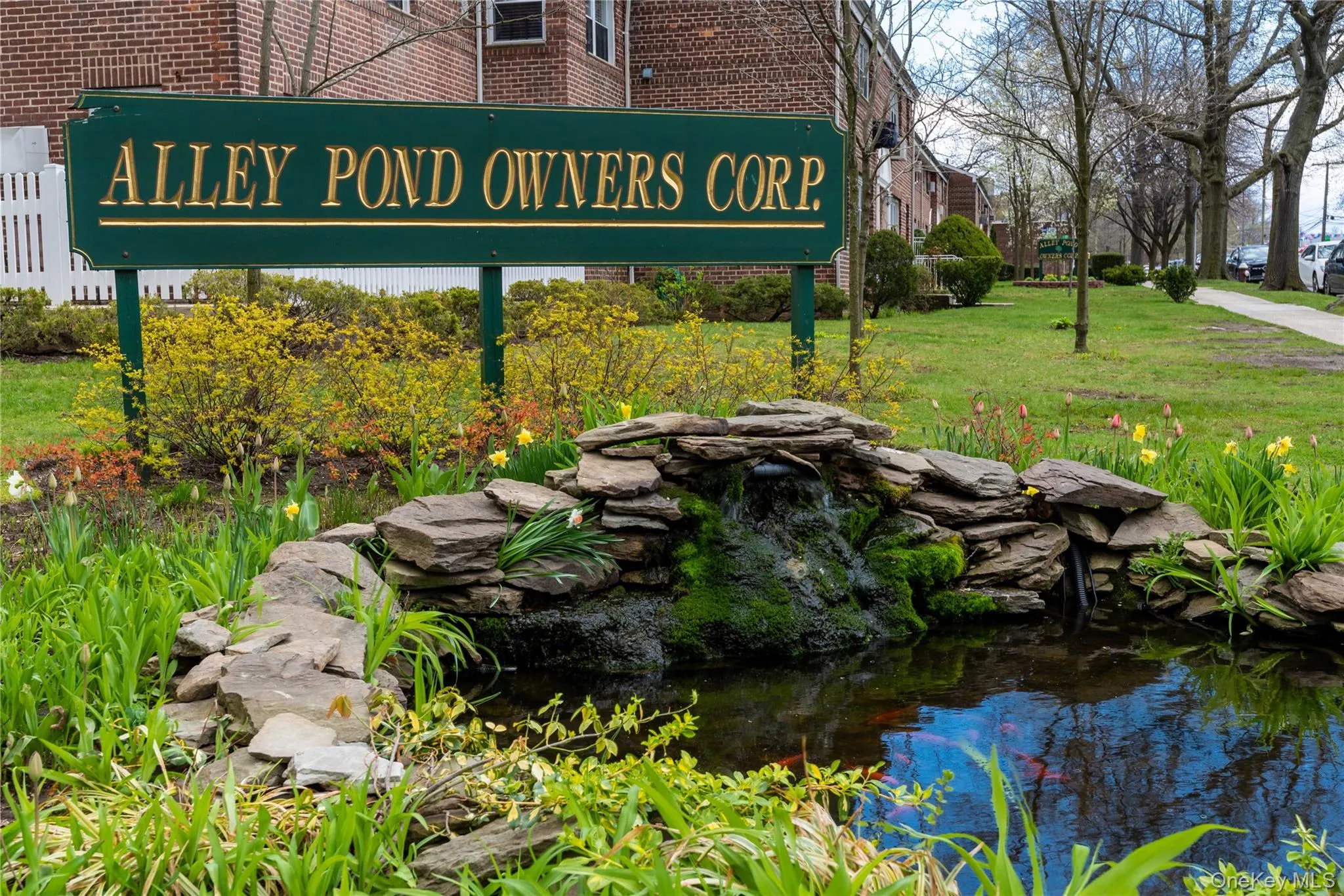 Stone water feature with a reflecting pond surrounded by lush greenery and flowering plants Stone water feature with a reflecting pond surrounded by lush greenery and flowering plants