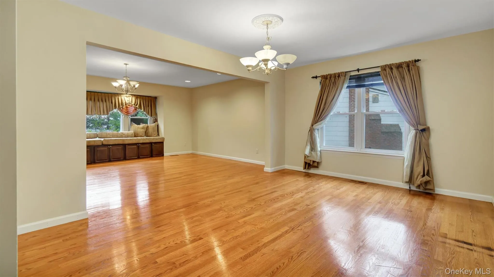 Spare room with a chandelier, light wood-style flooring, a wealth of natural light, and baseboards Spare room with a chandelier, light wood-style flooring, a wealth of natural light, and baseboards