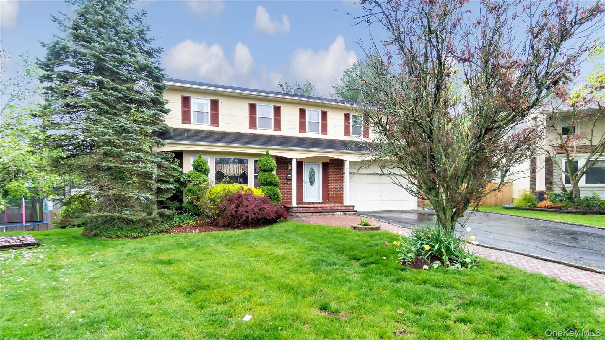 Traditional-style house featuring brick siding, a garage, a trampoline, a front yard, and aphalt driveway Traditional-style house featuring brick siding, a garage, a trampoline, a front yard, and aphalt driveway