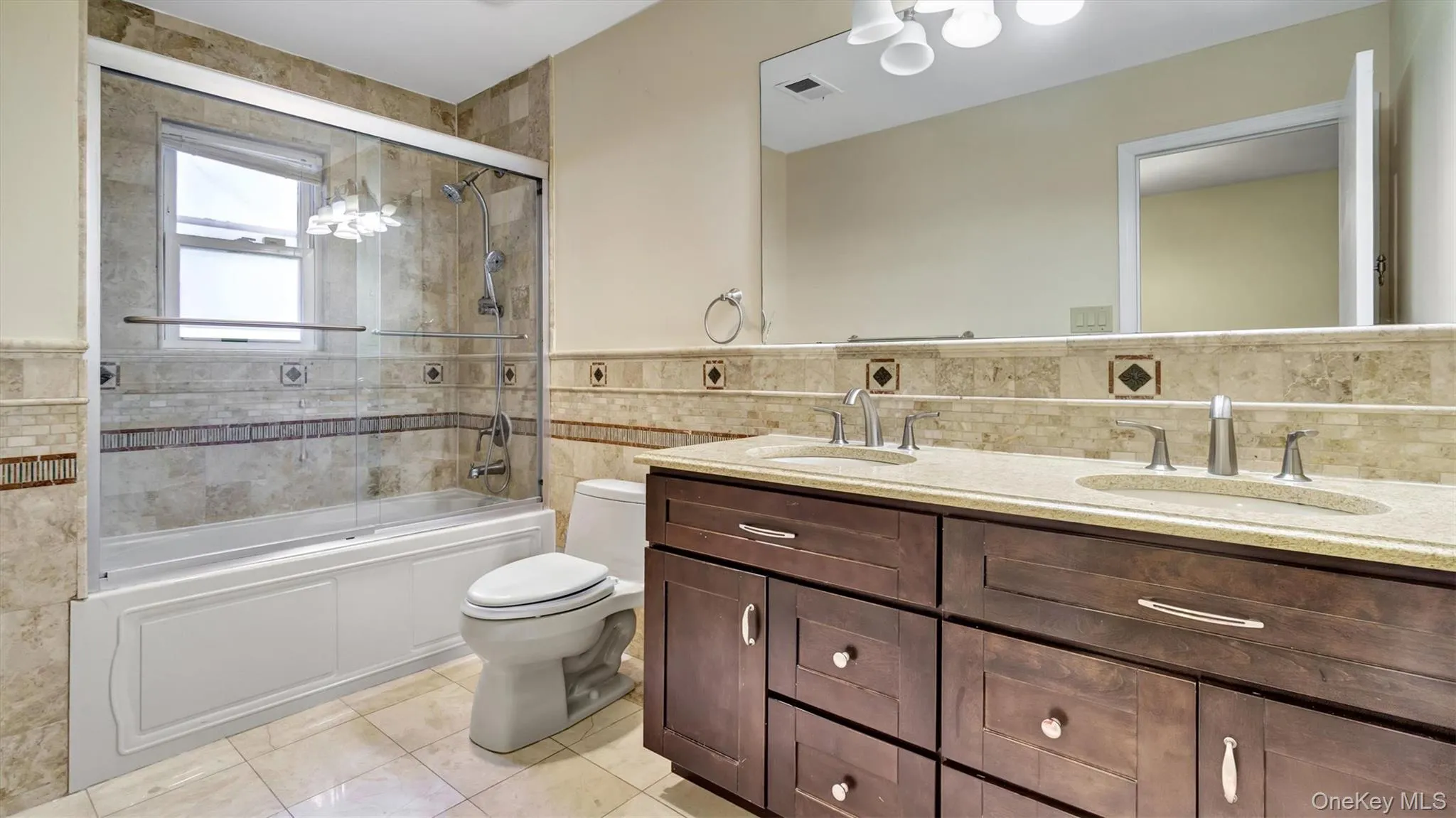 Full bathroom featuring toilet, a sink, tile walls, visible vents, and tile patterned flooring Full bathroom featuring toilet, a sink, tile walls, visible vents, and tile patterned flooring