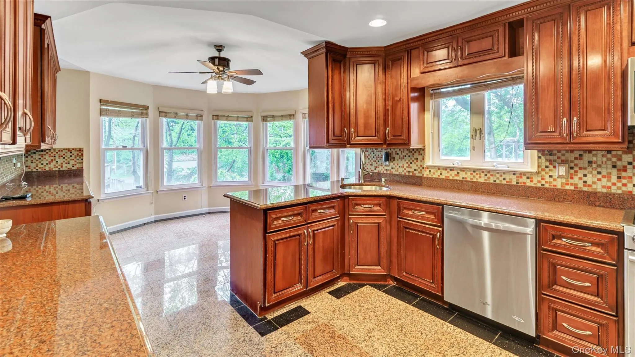 Kitchen featuring a wealth of natural light, granite finish floor, a ceiling fan, and dishwasher Kitchen featuring a wealth of natural light, granite finish floor, a ceiling fan, and dishwasher