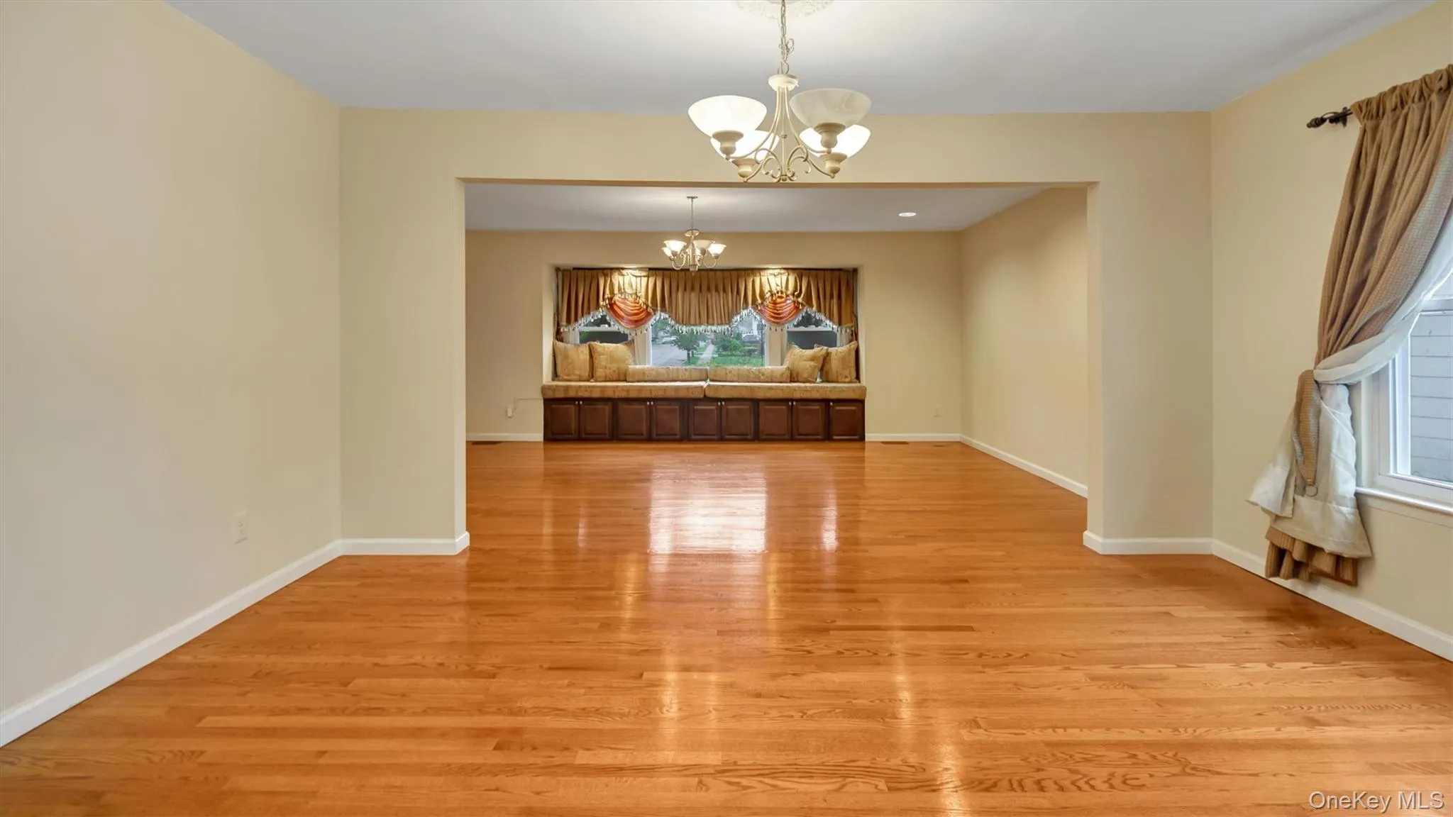 Unfurnished dining area featuring an inviting chandelier, baseboards, and light wood finished floors Unfurnished dining area featuring an inviting chandelier, baseboards, and light wood finished floors
