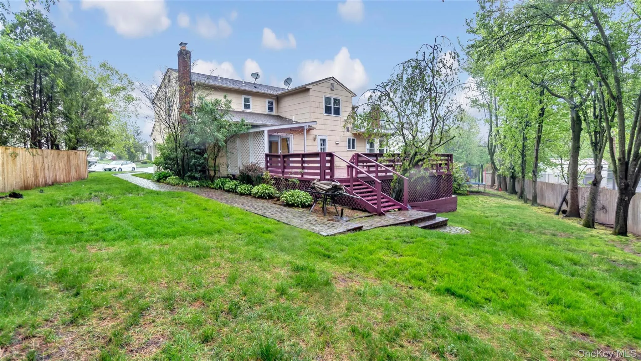 Rear view of house with a lawn, fence, a chimney, and a deck Rear view of house with a lawn, fence, a chimney, and a deck