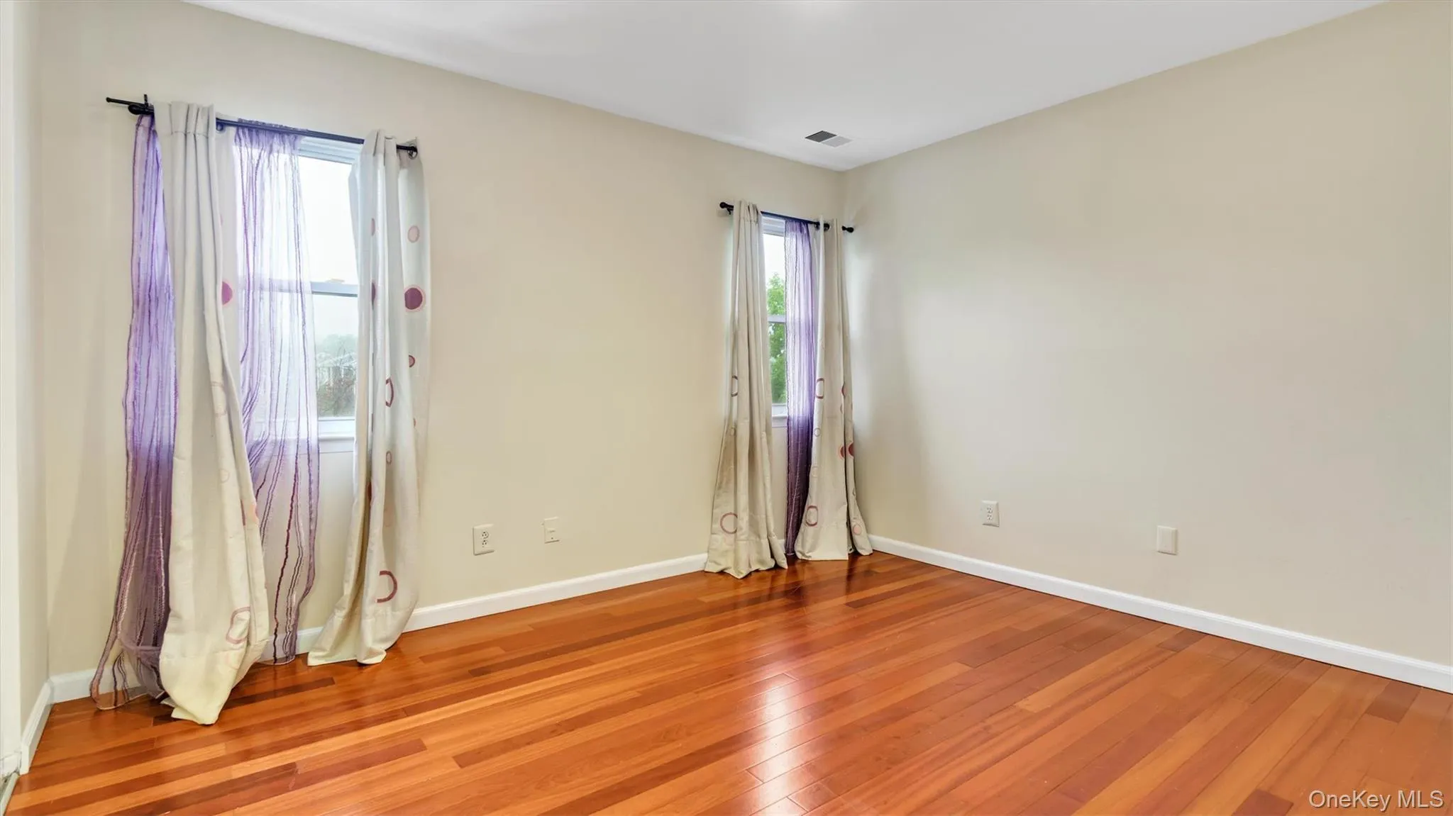 Spare room featuring light wood finished floors, baseboards, and visible vents Spare room featuring light wood finished floors, baseboards, and visible vents