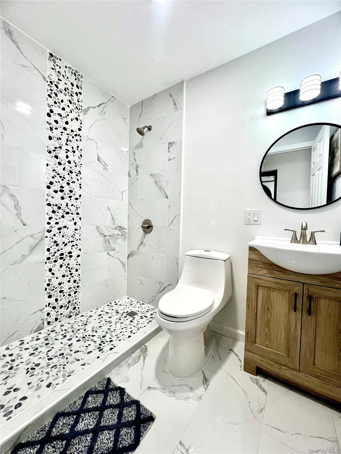 Bathroom featuring light marble finish floors, vanity, and a marble finish shower Bathroom featuring light marble finish floors, vanity, and a marble finish shower
