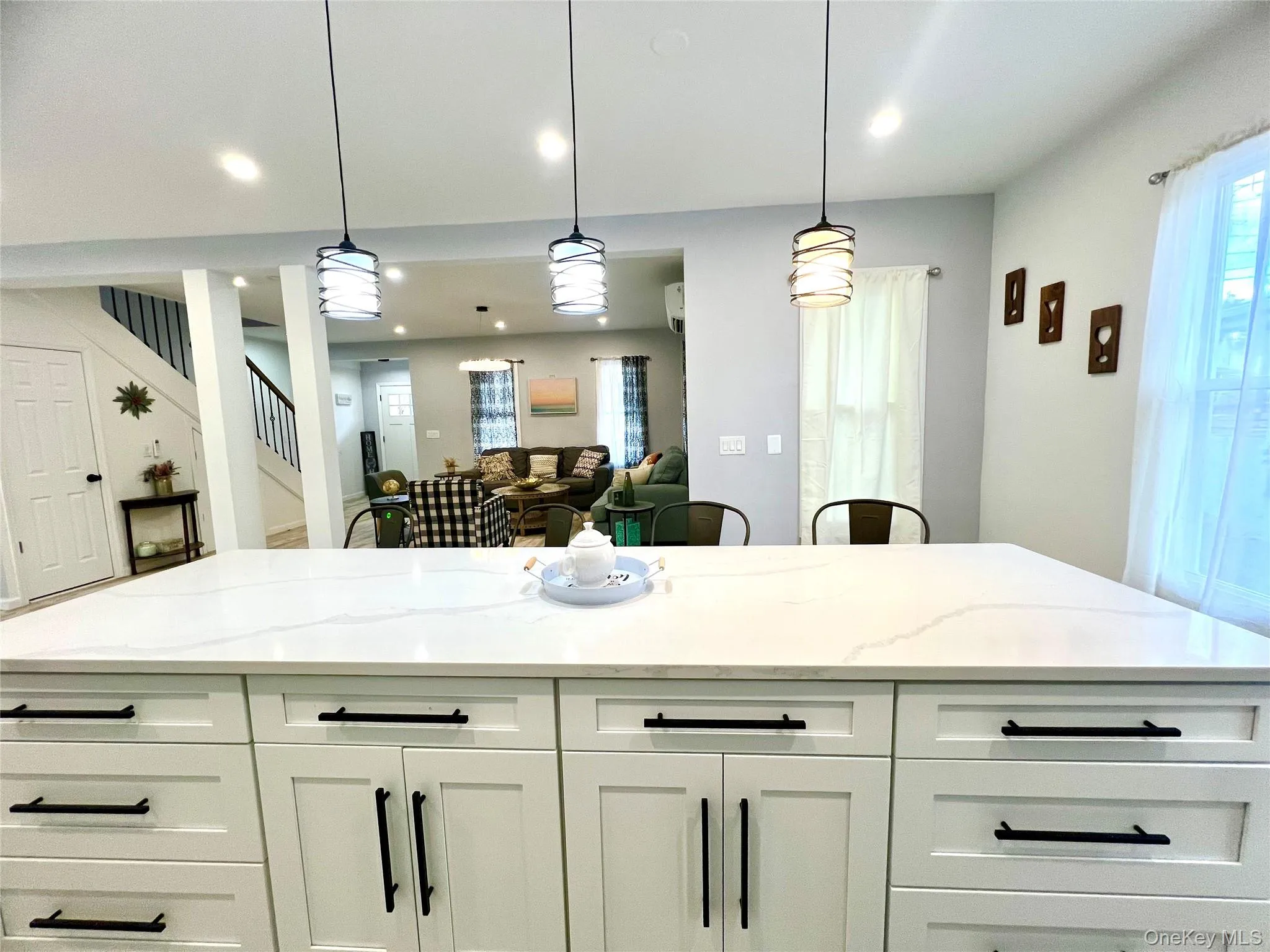 Kitchen featuring light stone countertops, white cabinets, hanging light fixtures, and a center island Kitchen featuring light stone countertops, white cabinets, hanging light fixtures, and a center island
