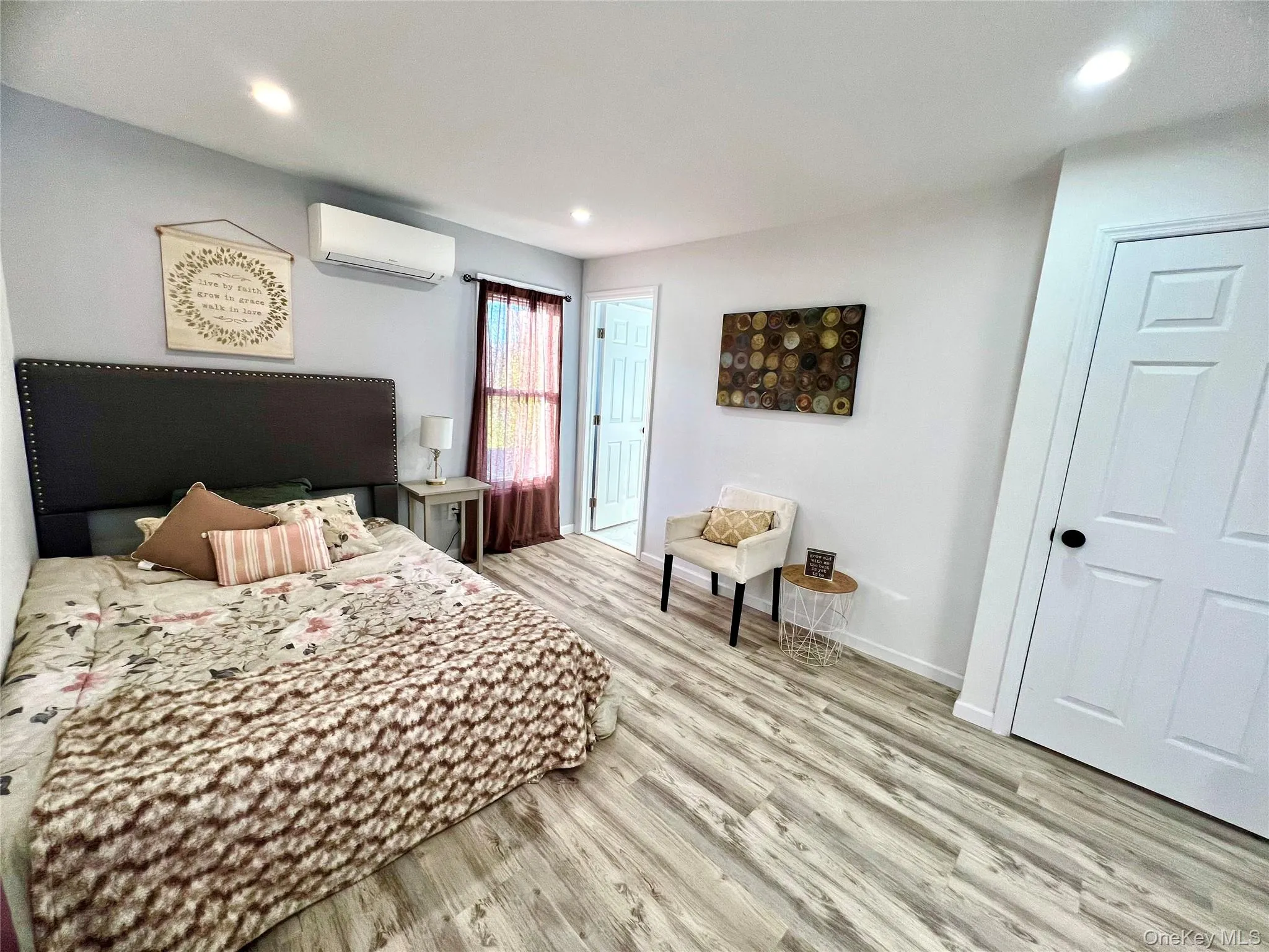 Bedroom with light wood-style flooring, recessed lighting, and a wall mounted air conditioner Bedroom with light wood-style flooring, recessed lighting, and a wall mounted air conditioner