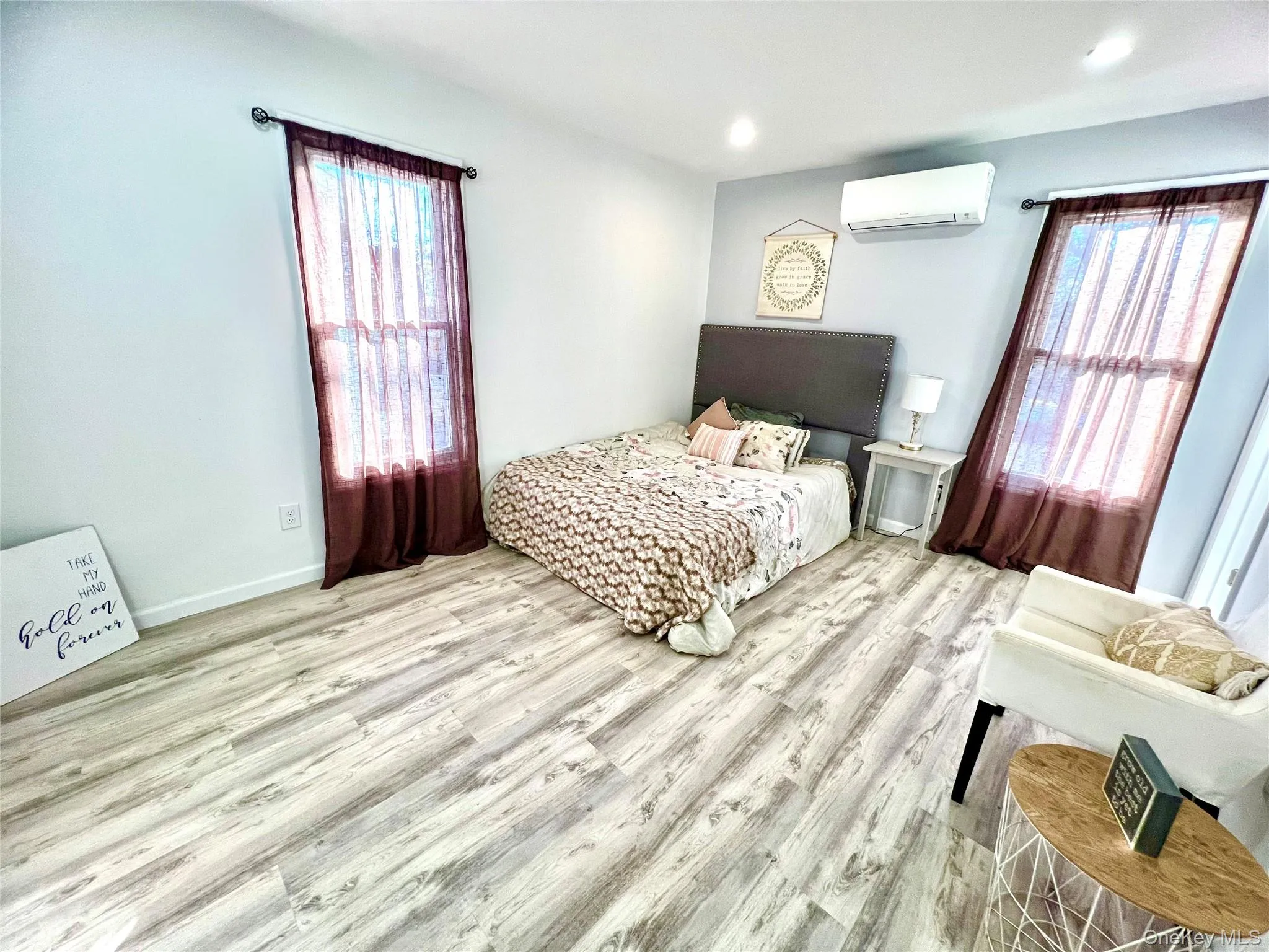 Bedroom featuring wood finished floors, recessed lighting, and an AC wall unit Bedroom featuring wood finished floors, recessed lighting, and an AC wall unit