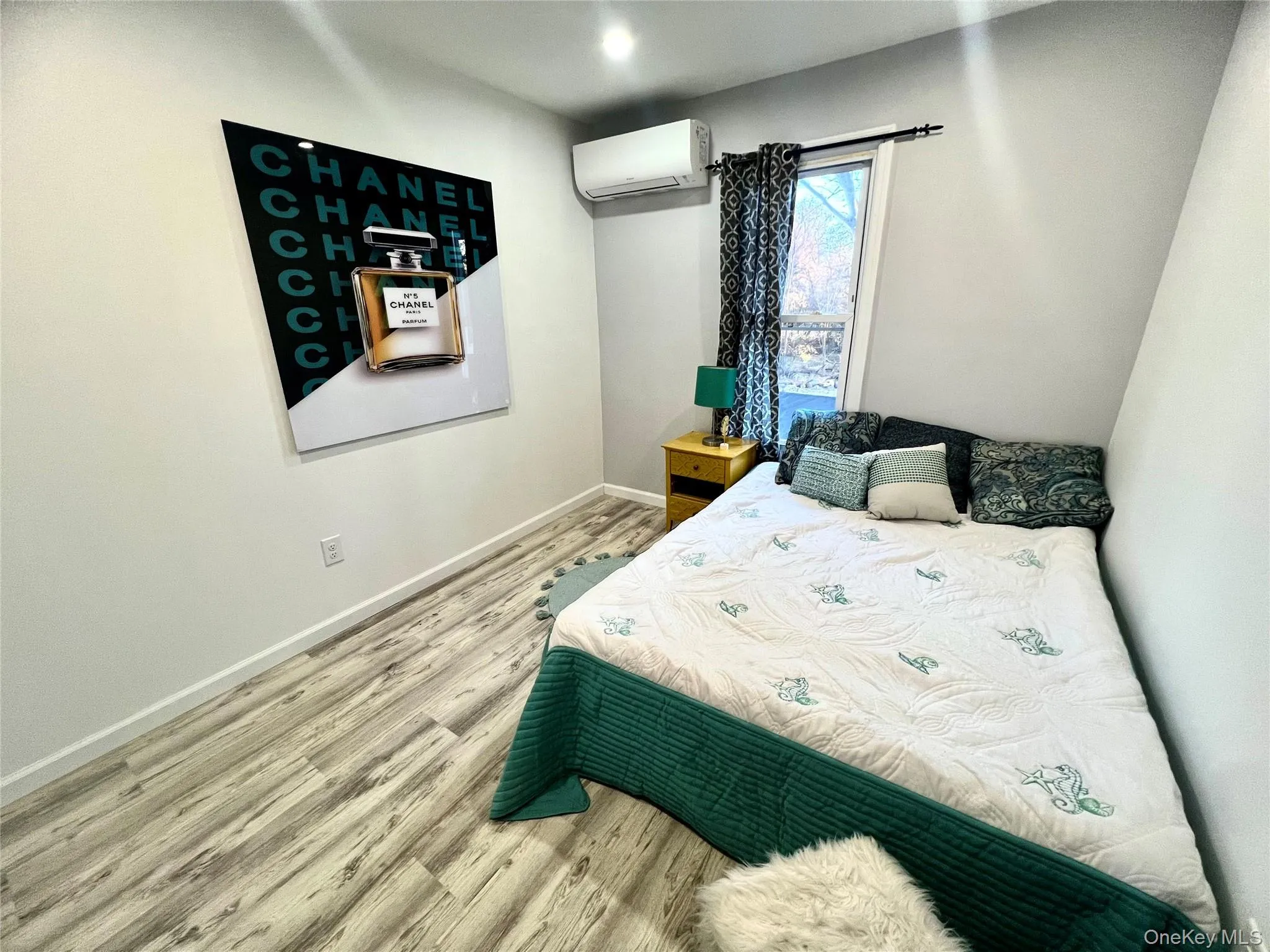 Bedroom featuring light wood finished floors and an AC wall unit Bedroom featuring light wood finished floors and an AC wall unit