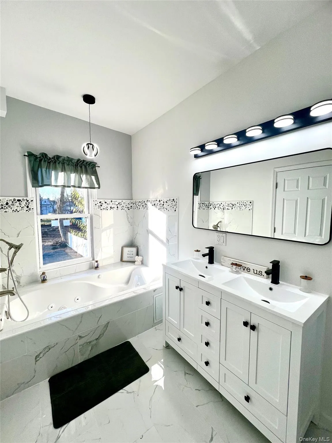 Bathroom featuring double vanity, light marble finish flooring, and a whirlpool tub Bathroom featuring double vanity, light marble finish flooring, and a whirlpool tub