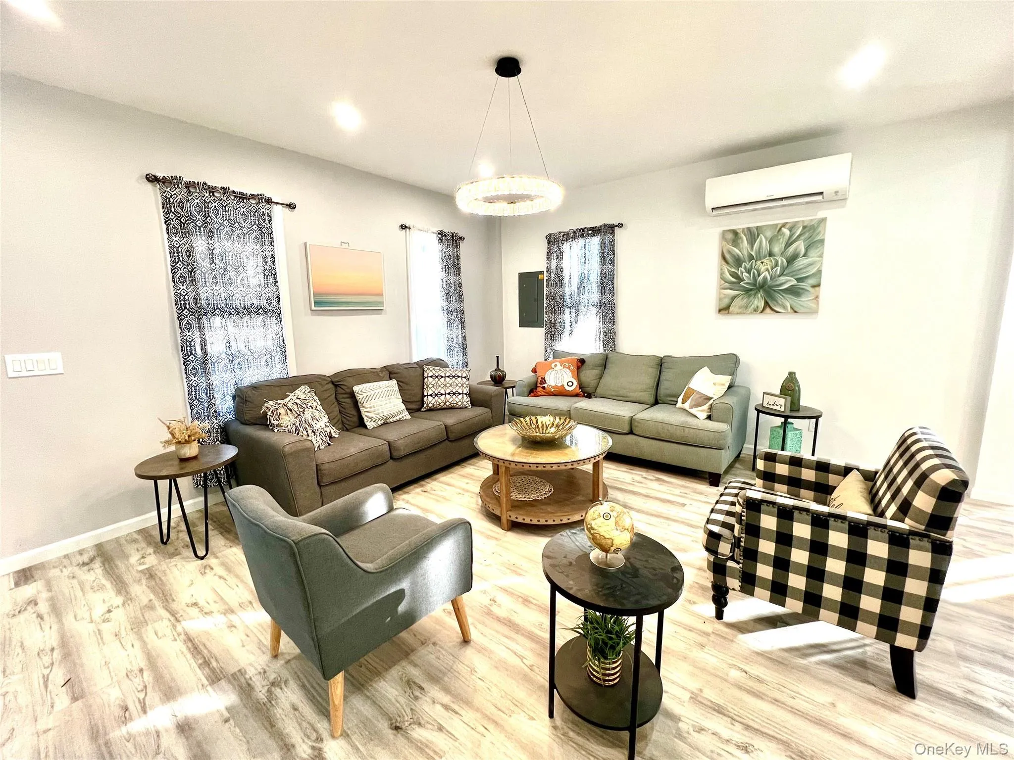 Living area with wood finished floors, a wall unit AC, recessed lighting, and electric panel Living area with wood finished floors, a wall unit AC, recessed lighting, and electric panel