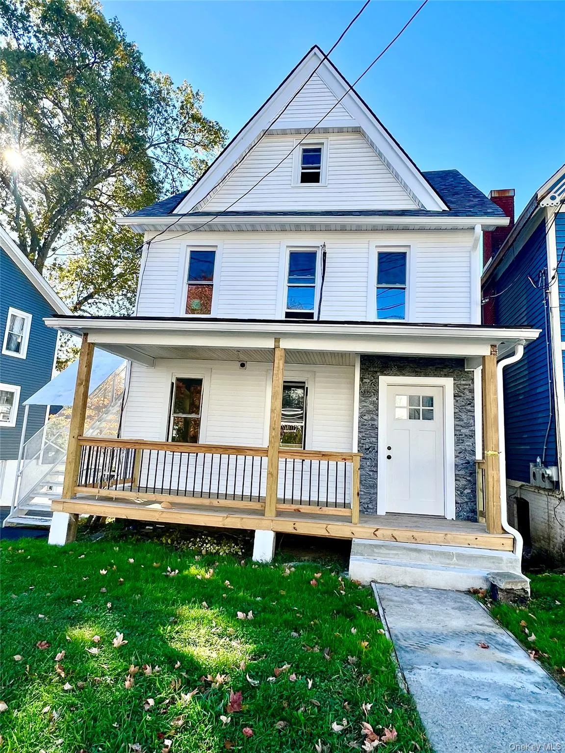View of front of house with a porch, stone siding, and a front yard View of front of house with a porch, stone siding, and a front yard