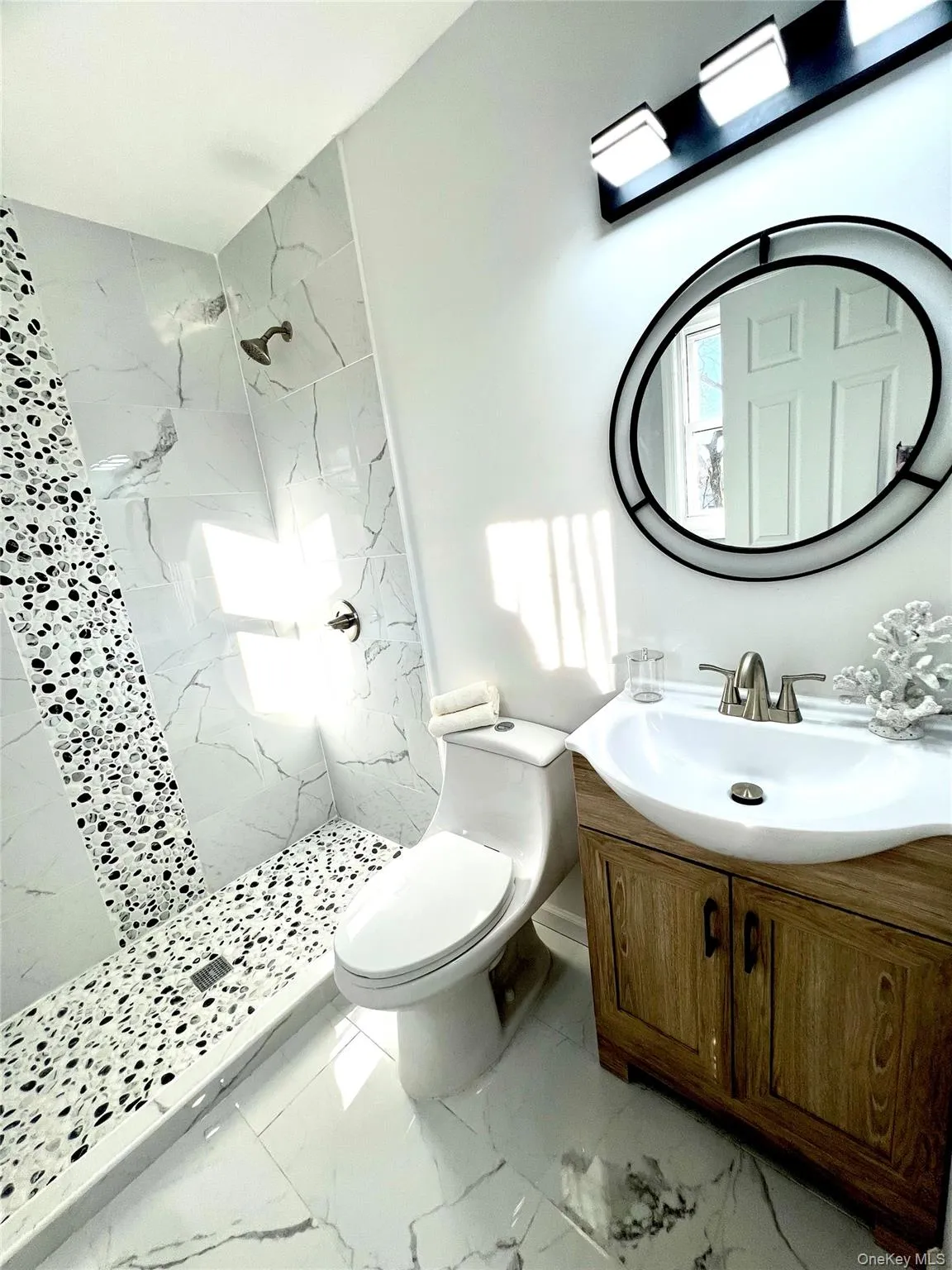 Full bathroom with vanity, a marble finish shower, and light marble finish floors Full bathroom with vanity, a marble finish shower, and light marble finish floors