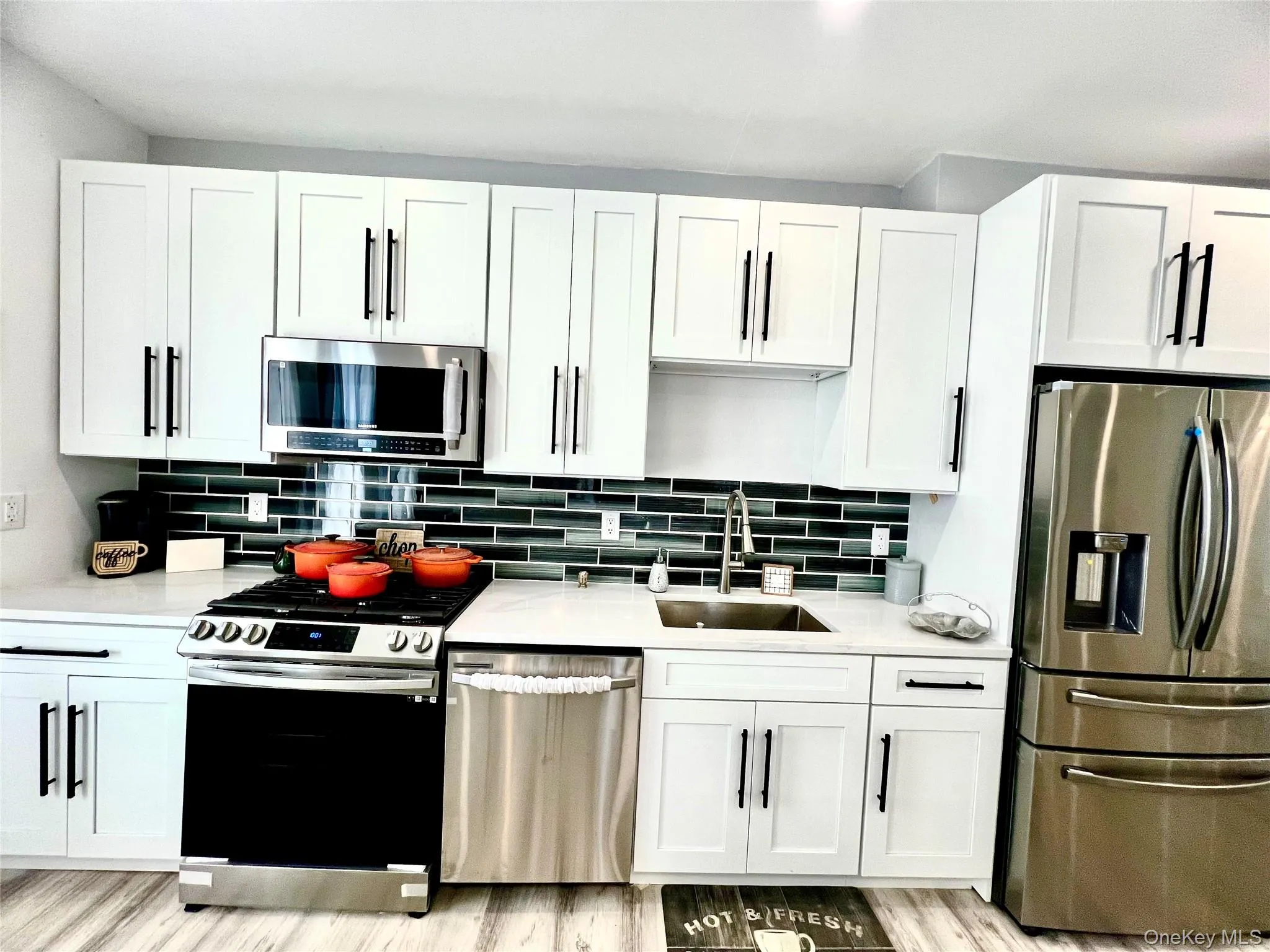 Kitchen featuring appliances with stainless steel finishes, white cabinetry, light stone countertops, and decorative backsplash Kitchen featuring appliances with stainless steel finishes, white cabinetry, light stone countertops, and decorative backsplash