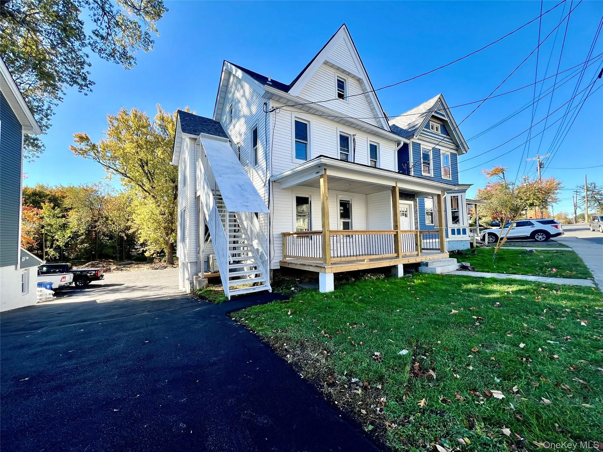 View of front of home featuring a front lawn, covered porch, and stairway View of front of home featuring a front lawn, covered porch, and stairway