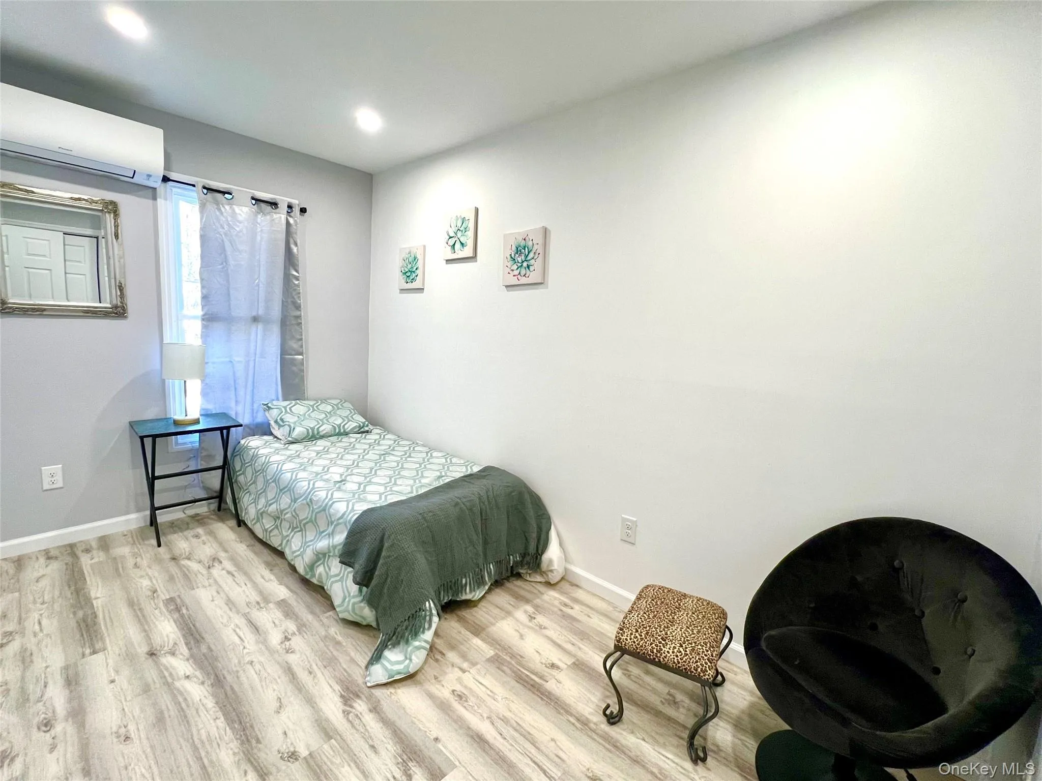 Bedroom featuring a wall mounted AC and wood finished floors Bedroom featuring a wall mounted AC and wood finished floors