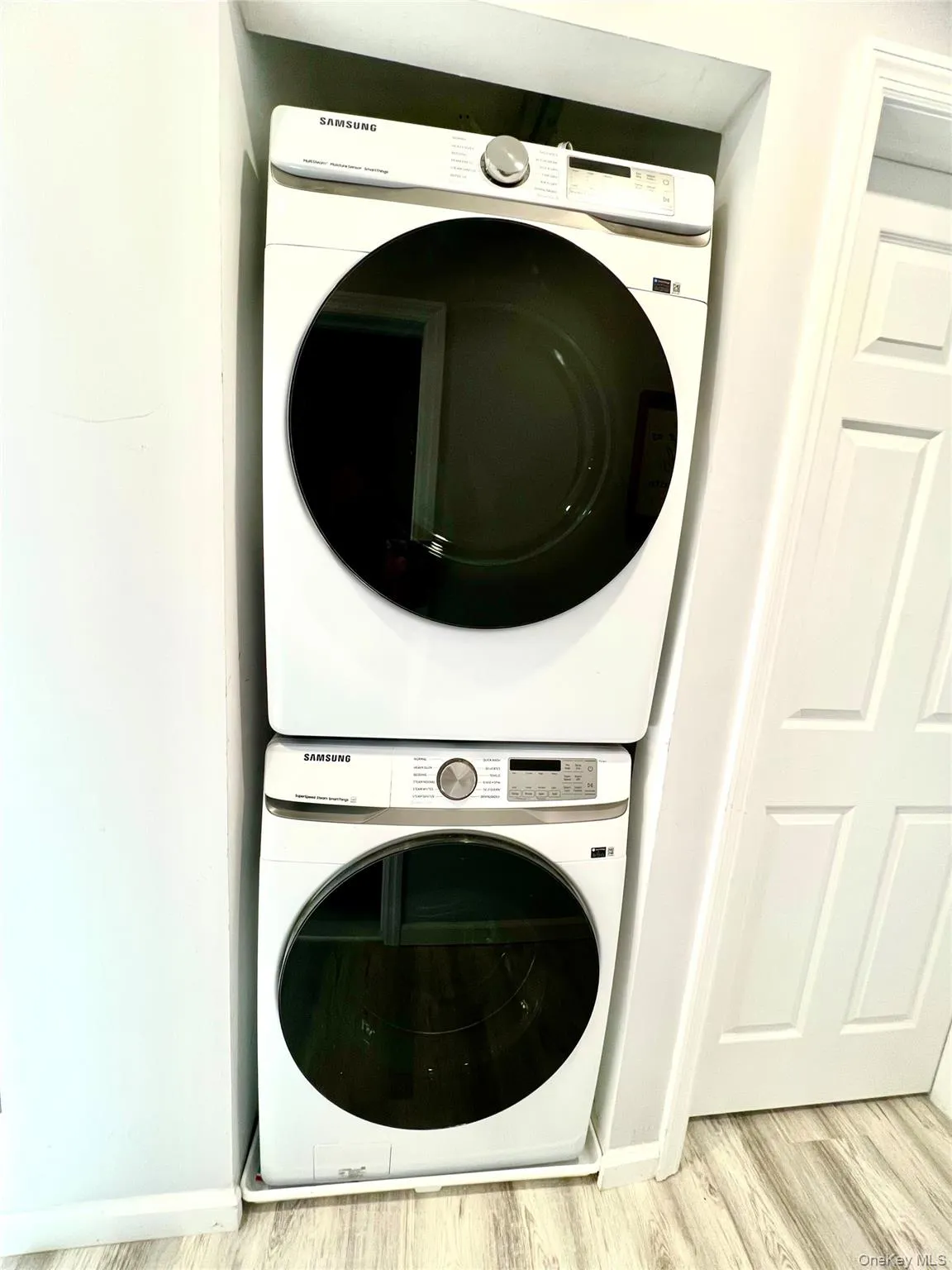 Laundry room with stacked washer / dryer and light wood finished floors Laundry room with stacked washer / dryer and light wood finished floors
