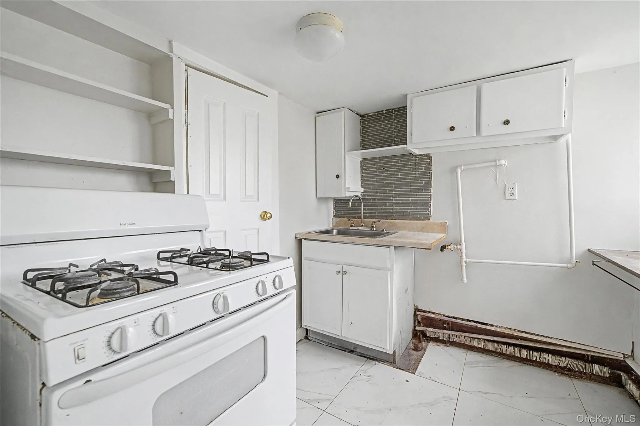 Kitchen featuring a gas range, white cabinetry, a sink with exposed plumbing, and a tiled floor Kitchen featuring a gas range, white cabinetry, a sink with exposed plumbing, and a tiled floor