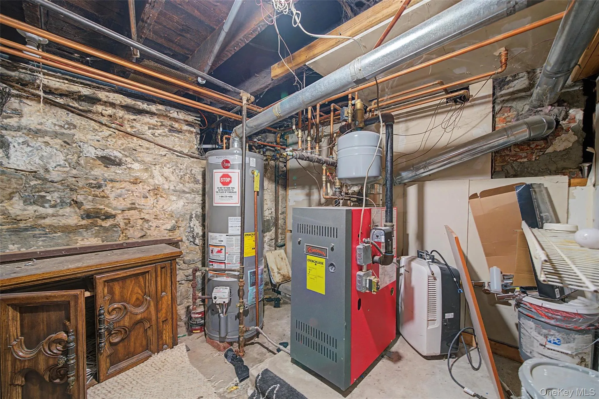 Utility room featuring a water heater, boiler, and exposed copper piping Utility room featuring a water heater, boiler, and exposed copper piping