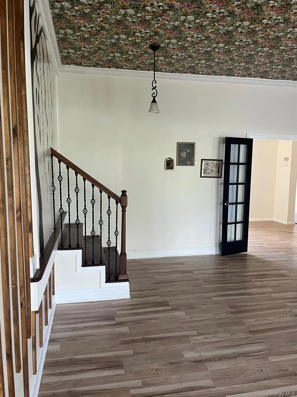 Interior space featuring wood-finish flooring, a staircase with dark wood handrails and wrought iron balusters, and a black multi-pane door Interior space featuring wood-finish flooring, a staircase with dark wood handrails and wrought iron balusters, and a black multi-pane door