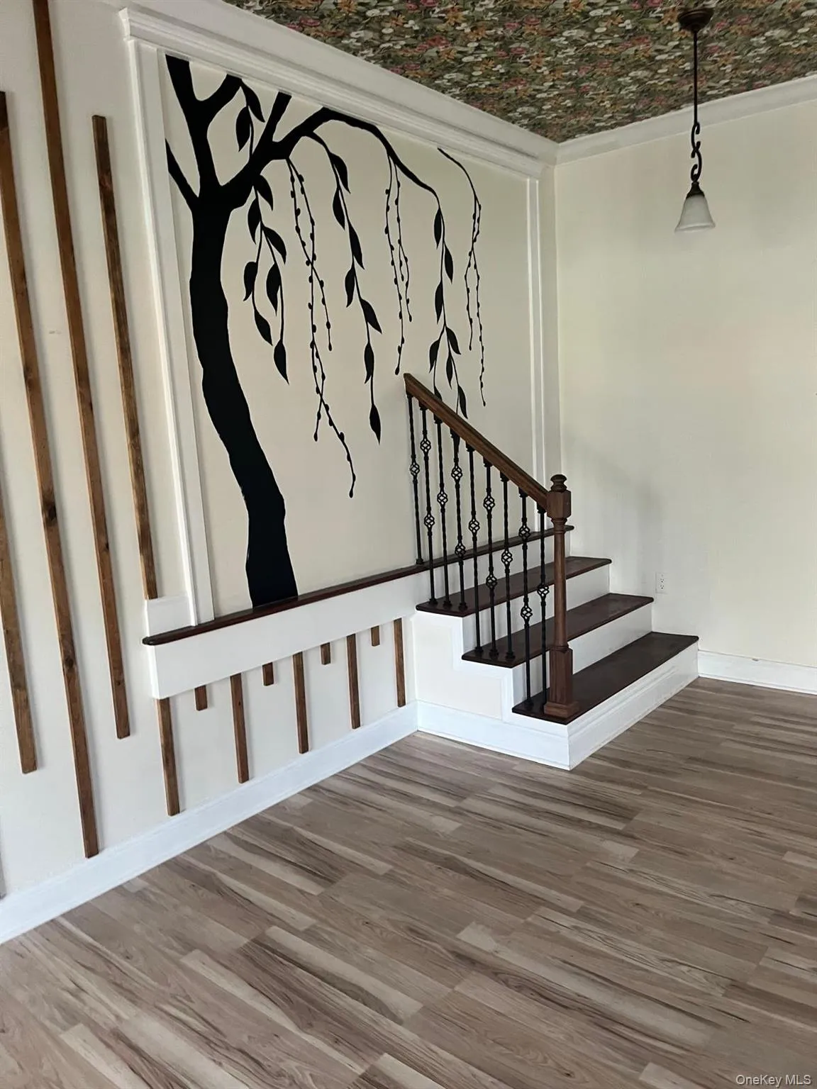 Entry area with wood-finish flooring, a decorative wall mural, and crown molding Entry area with wood-finish flooring, a decorative wall mural, and crown molding