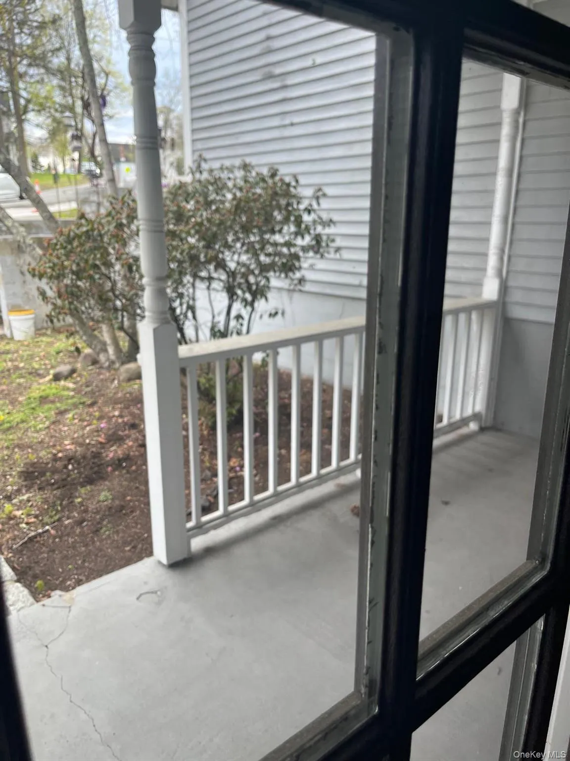 Front porch with white painted balusters and posts, featuring a concrete surface Front porch with white painted balusters and posts, featuring a concrete surface