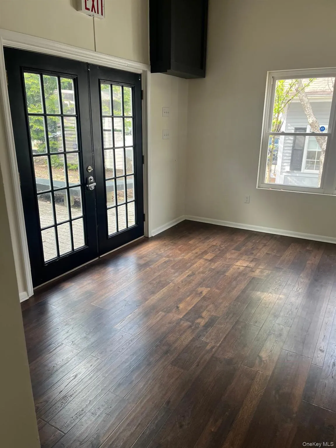 Room featuring wood-finish flooring, light neutral wall paint, and white trim Room featuring wood-finish flooring, light neutral wall paint, and white trim