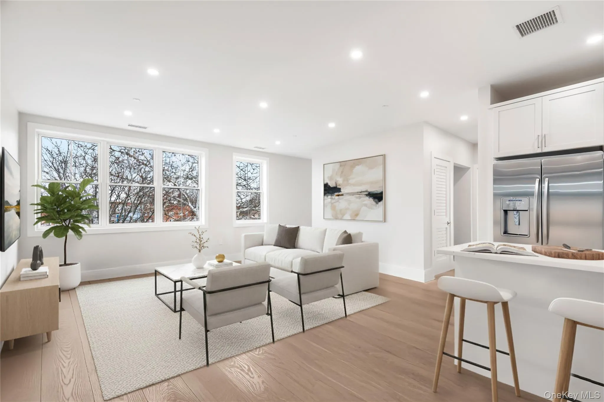 Living room with light wood-type flooring and recessed lighting. Large windows make it bright and airy allowing for tons of natural light to flow through. Digitally staged. Living room with light wood-type flooring and recessed lighting. Large windows make it bright and airy allowing for tons of natural light to flow through. Digitally staged.