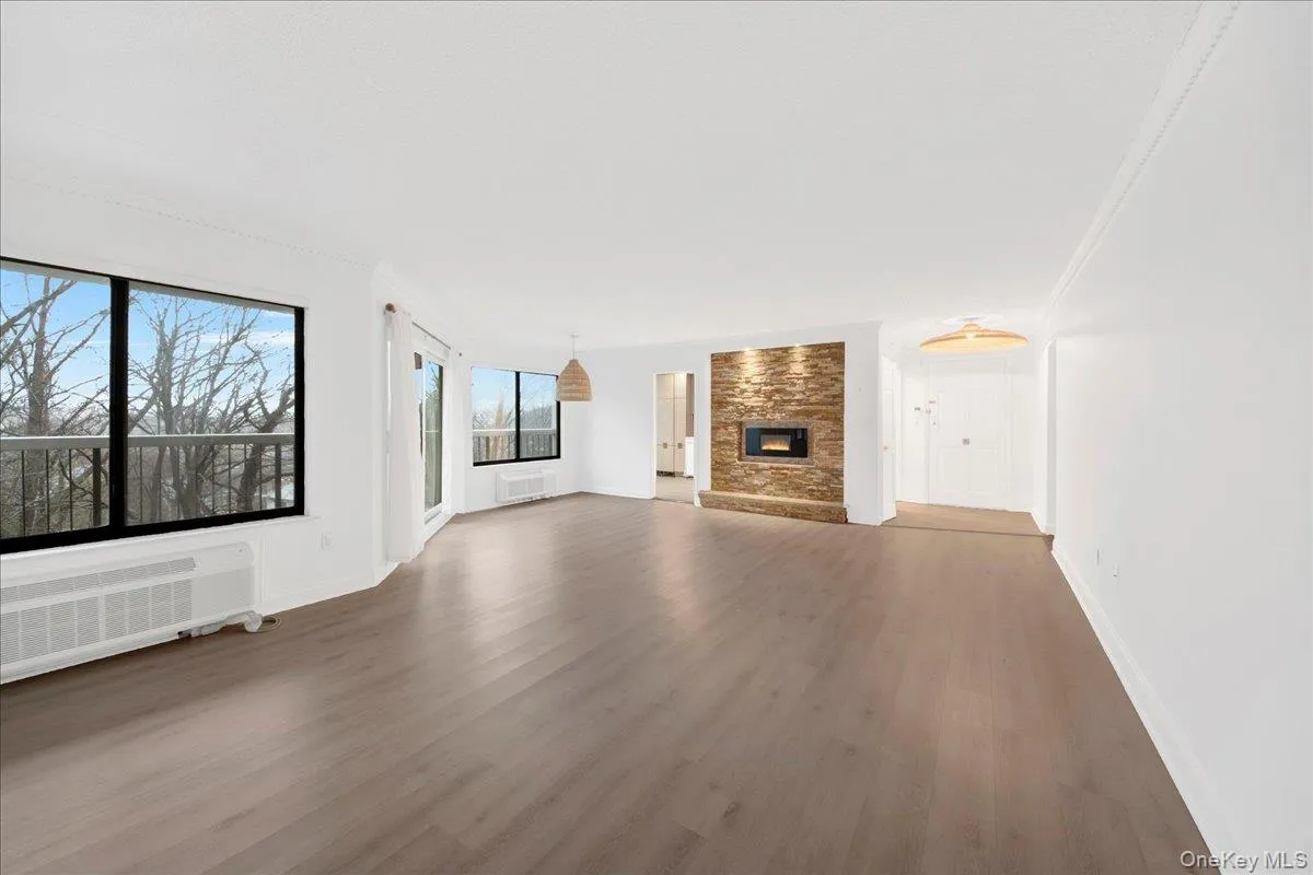 Unfurnished living room featuring crown molding, dark wood-style floors, a fireplace, and radiator Unfurnished living room featuring crown molding, dark wood-style floors, a fireplace, and radiator