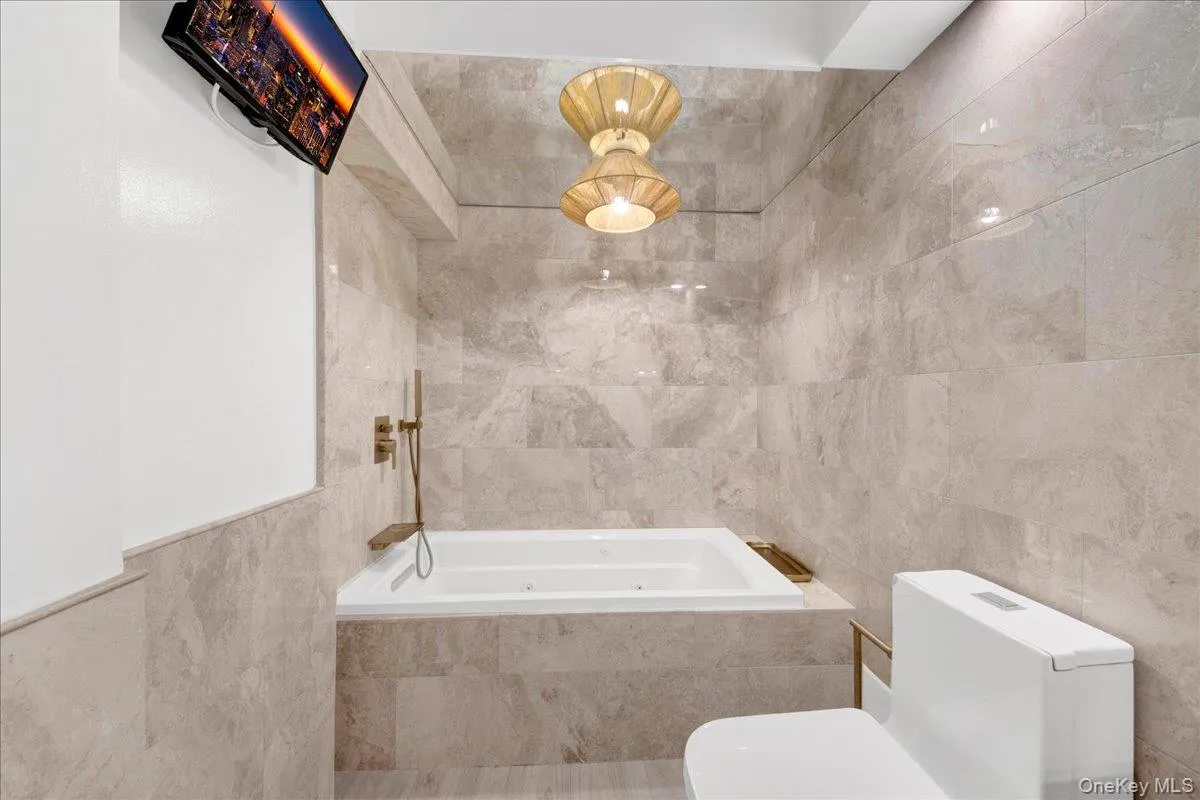 Bathroom featuring tile walls and a tub with jets Bathroom featuring tile walls and a tub with jets