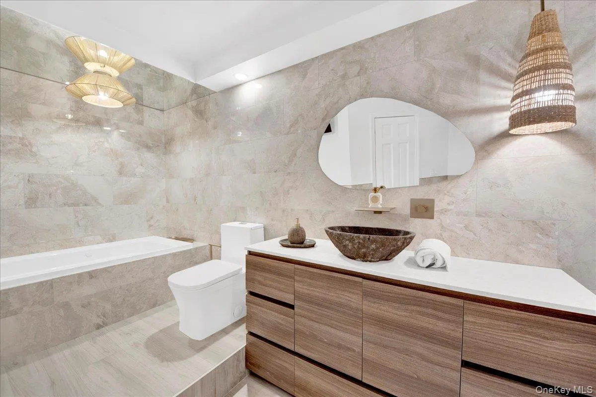 Full bath with tile walls, vanity, and a relaxing tiled tub Full bath with tile walls, vanity, and a relaxing tiled tub