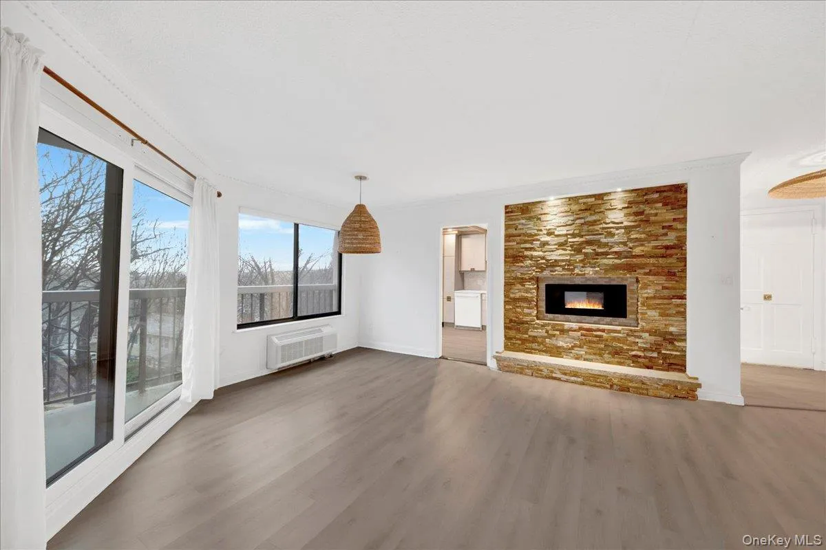 Unfurnished living room with dark wood-style flooring, ornamental molding, and a glass covered fireplace Unfurnished living room with dark wood-style flooring, ornamental molding, and a glass covered fireplace