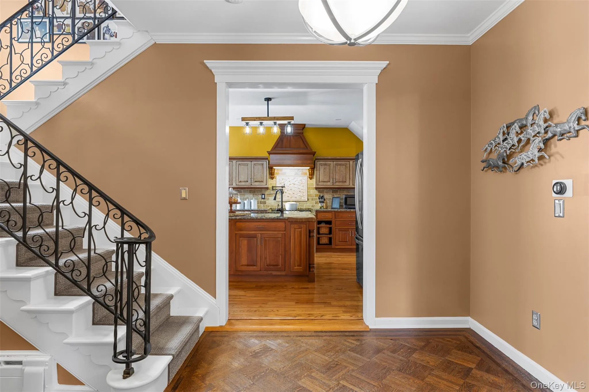 Grand stairway and hallway featuring parquet flooring and ornamental molding Grand stairway and hallway featuring parquet flooring and ornamental molding
