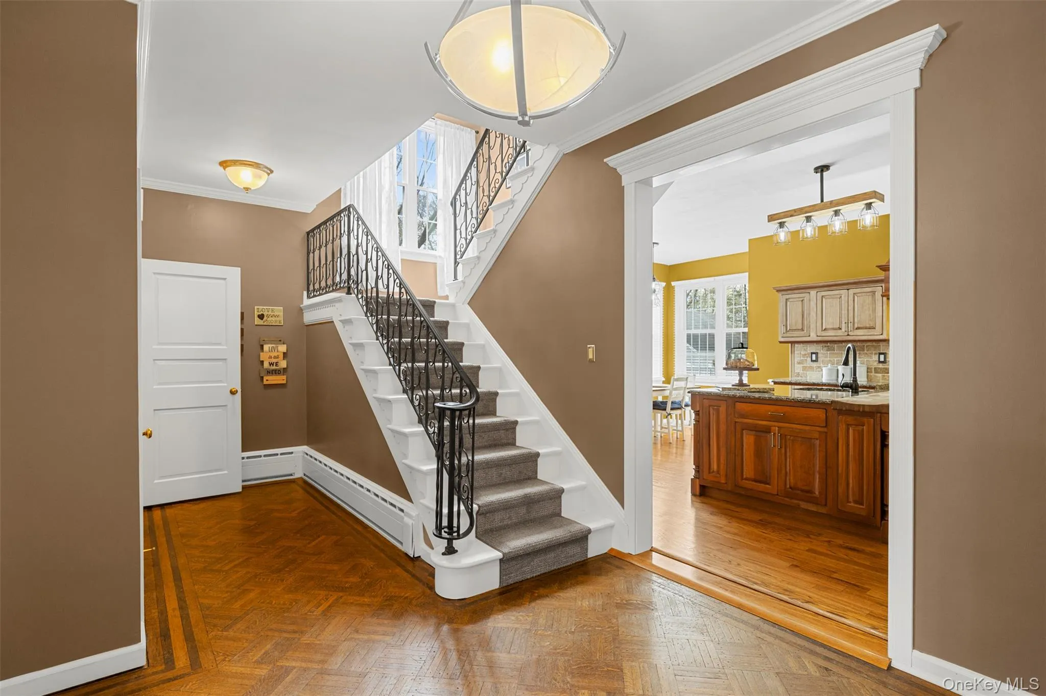 Grand stairway and hallway featuring parquet flooring and ornamental molding Grand stairway and hallway featuring parquet flooring and ornamental molding