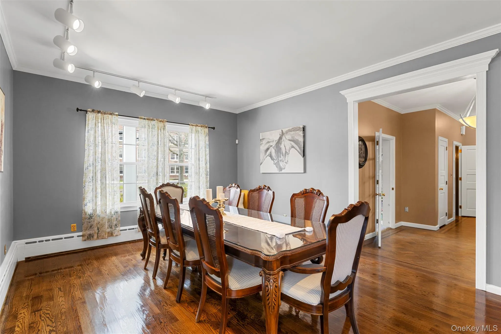 Formal dining room with wood finished floors, rail lighting, and crown molding Formal dining room with wood finished floors, rail lighting, and crown molding