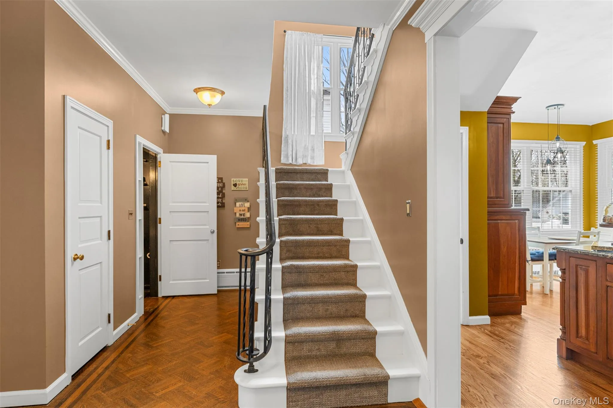 Grand stairway and hallway featuring parquet flooring and ornamental molding Grand stairway and hallway featuring parquet flooring and ornamental molding
