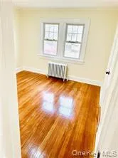 Empty room featuring radiator, baseboards, and wood finished floors Empty room featuring radiator, baseboards, and wood finished floors