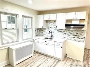 Kitchen with a sink, decorative backsplash, white cabinets, light countertops, and ventilation hood Kitchen with a sink, decorative backsplash, white cabinets, light countertops, and ventilation hood