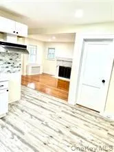 Unfurnished living room featuring a fireplace with flush hearth and wood finished floors Unfurnished living room featuring a fireplace with flush hearth and wood finished floors