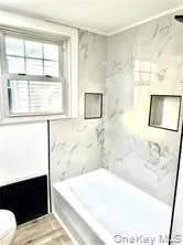 Full bath featuring a fireplace, toilet, wood finished floors, a shower, and a tub to relax in Full bath featuring a fireplace, toilet, wood finished floors, a shower, and a tub to relax in