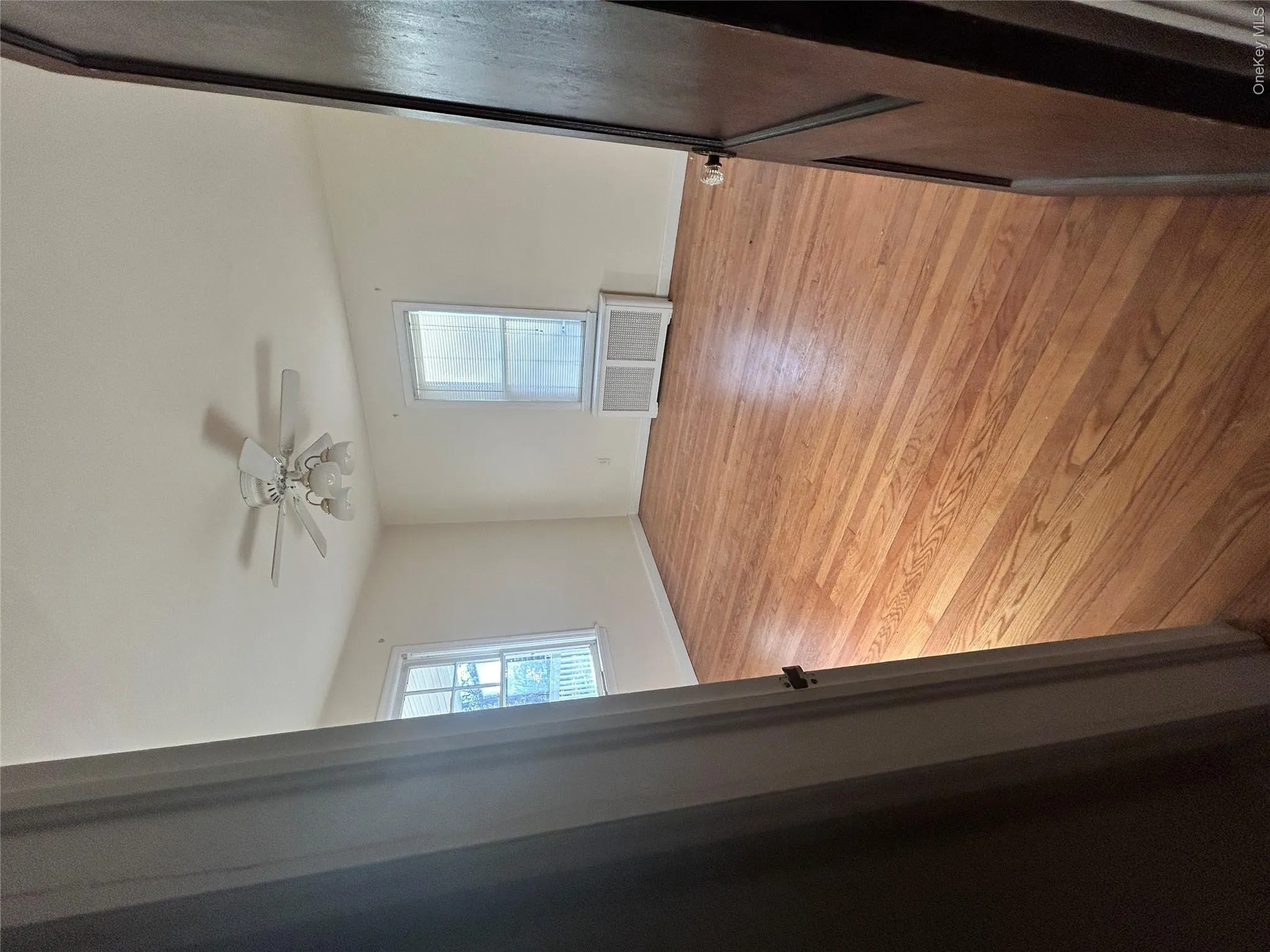 Empty room with healthy amount of natural light, light wood finished floors, a ceiling fan, and radiator Empty room with healthy amount of natural light, light wood finished floors, a ceiling fan, and radiator