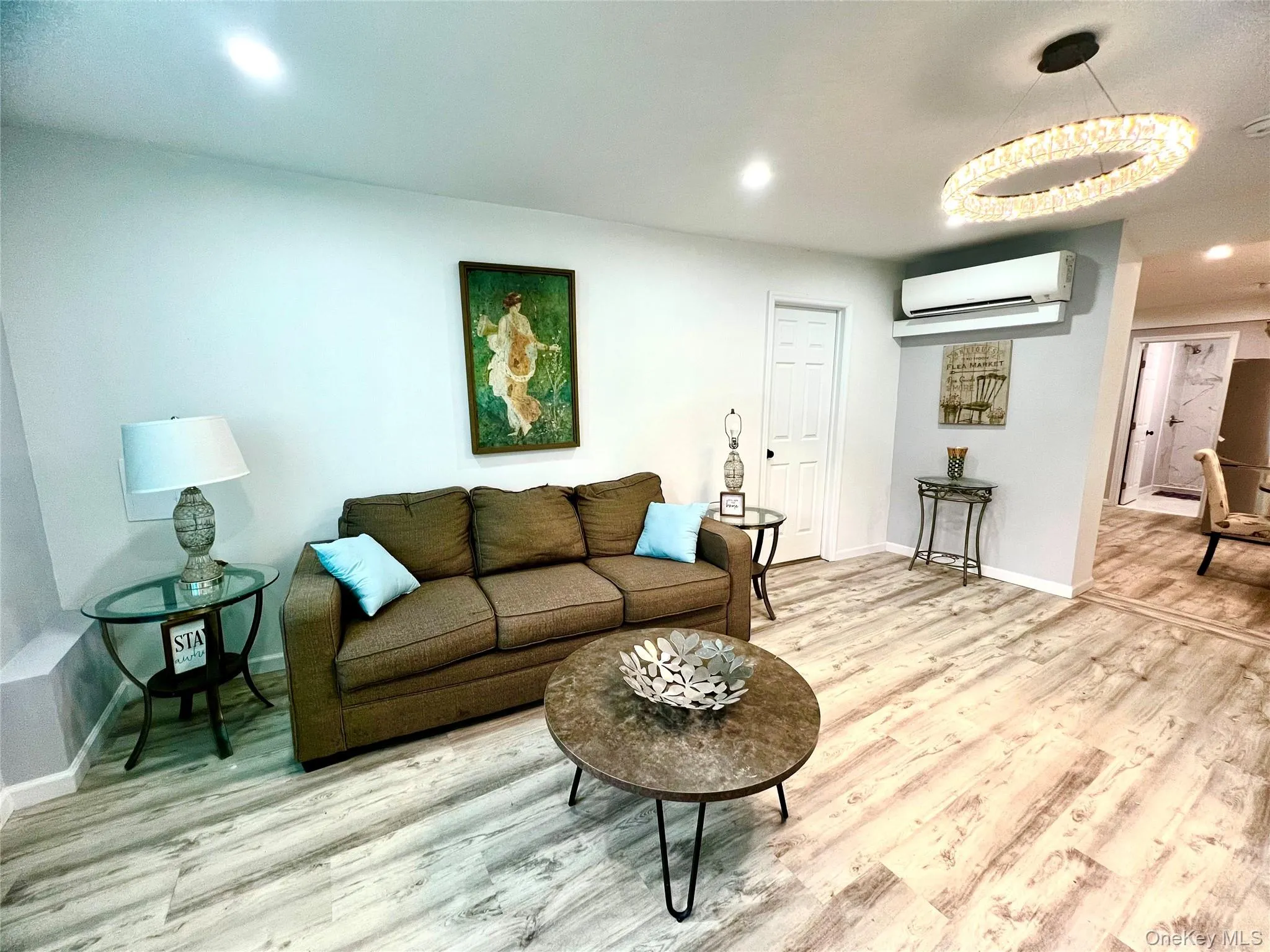 Living room featuring light wood-style flooring, recessed lighting, and a wall mounted AC Living room featuring light wood-style flooring, recessed lighting, and a wall mounted AC
