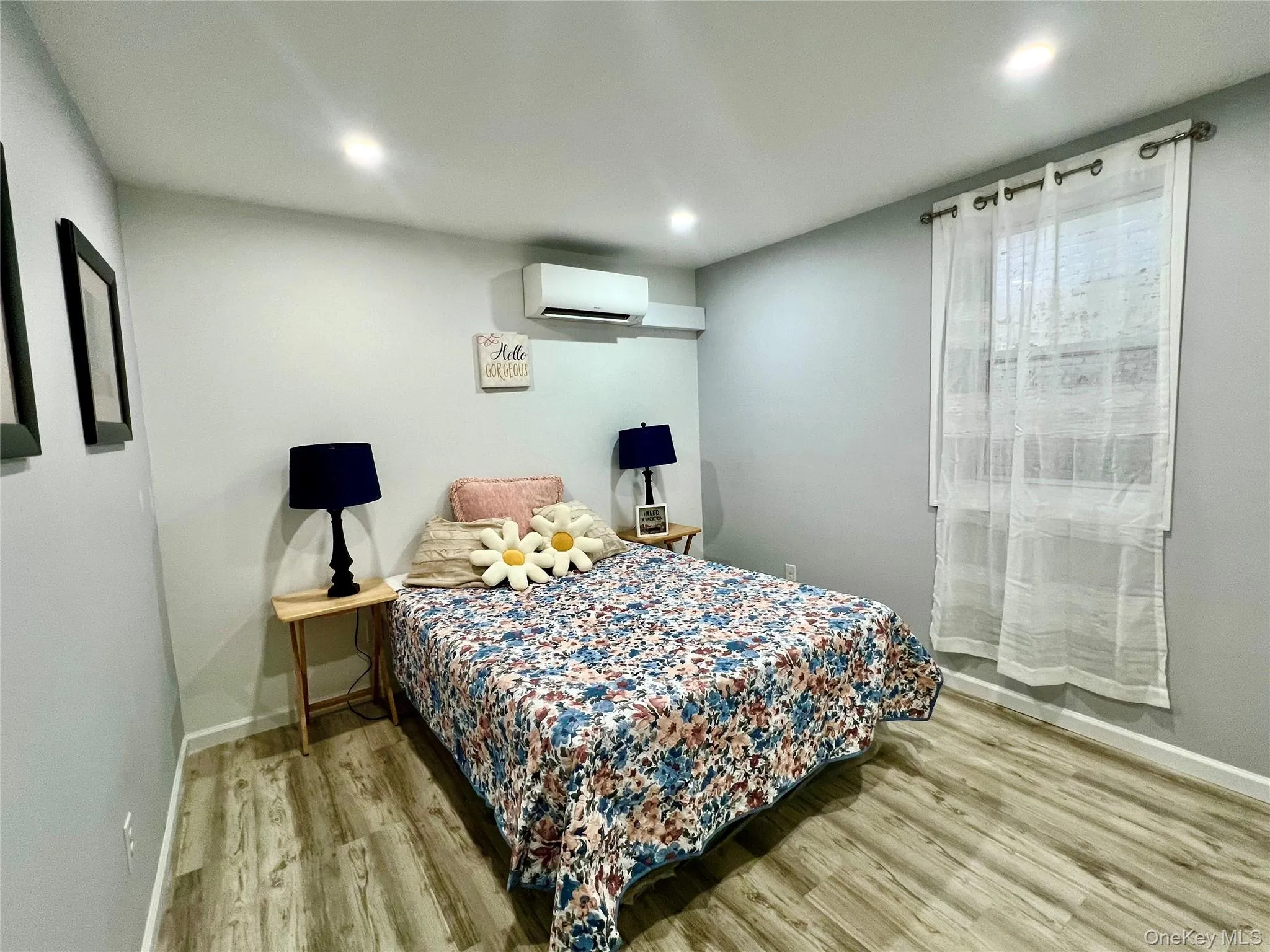 Bedroom with light wood-style flooring and a wall mounted air conditioner Bedroom with light wood-style flooring and a wall mounted air conditioner