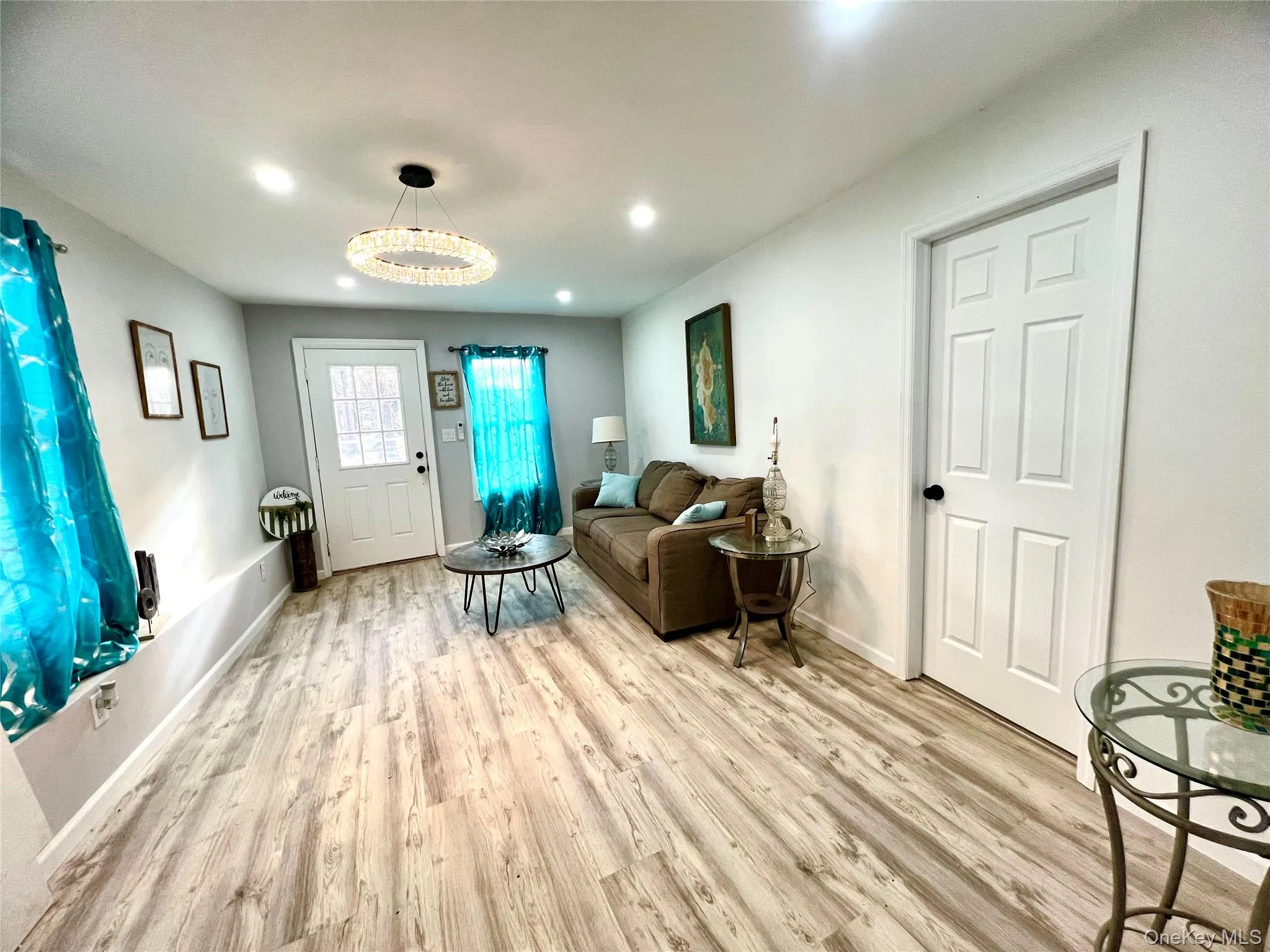 Living room with light wood-style floors, recessed lighting, and a chandelier Living room with light wood-style floors, recessed lighting, and a chandelier