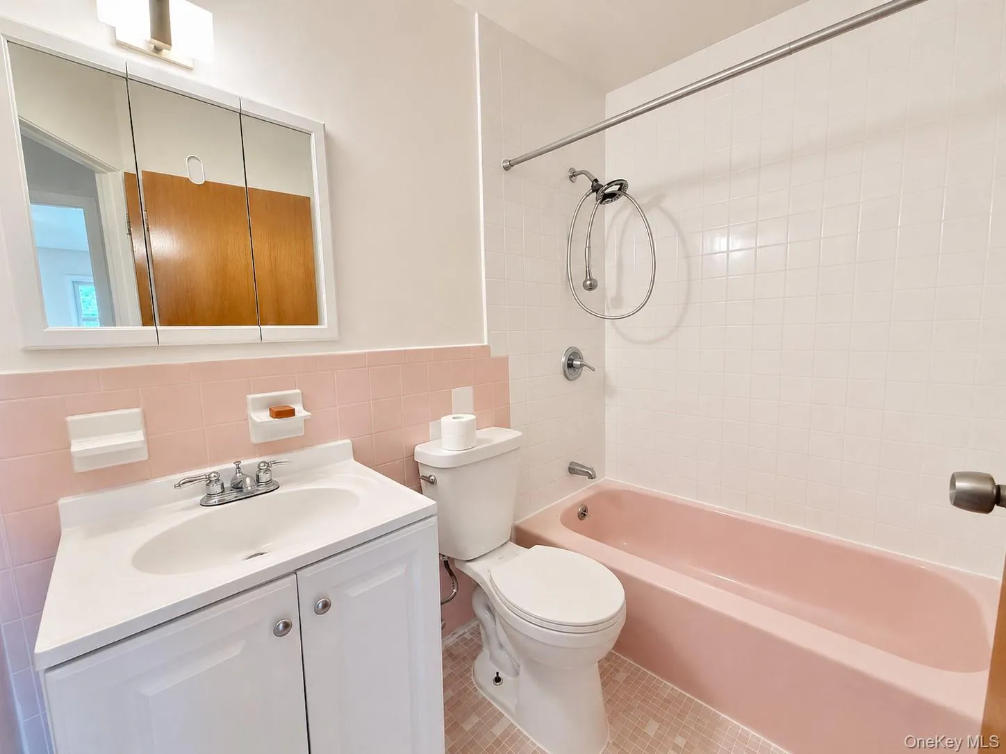 Bathroom featuring a white vanity with integrated sink, chrome faucet, and mirrored medicine cabinet Bathroom featuring a white vanity with integrated sink, chrome faucet, and mirrored medicine cabinet
