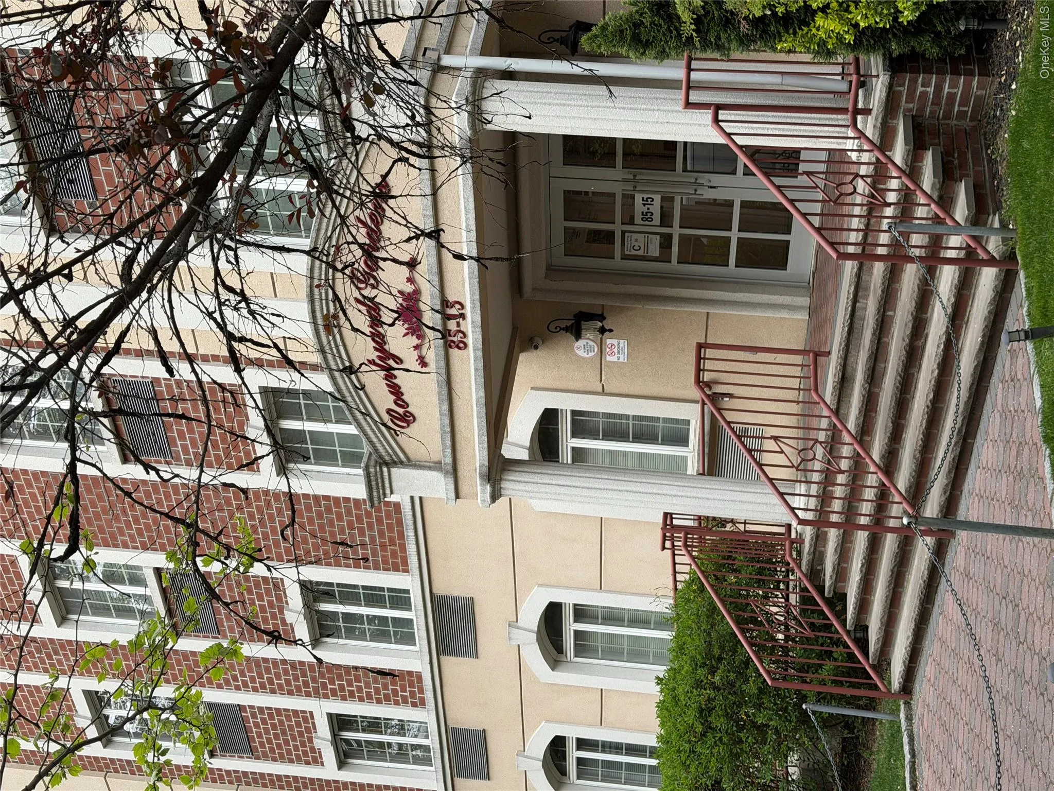 Building entrance featuring a brick facade with light-colored trim and a prominent "Courtyard Gardens" sign Building entrance featuring a brick facade with light-colored trim and a prominent "Courtyard Gardens" sign