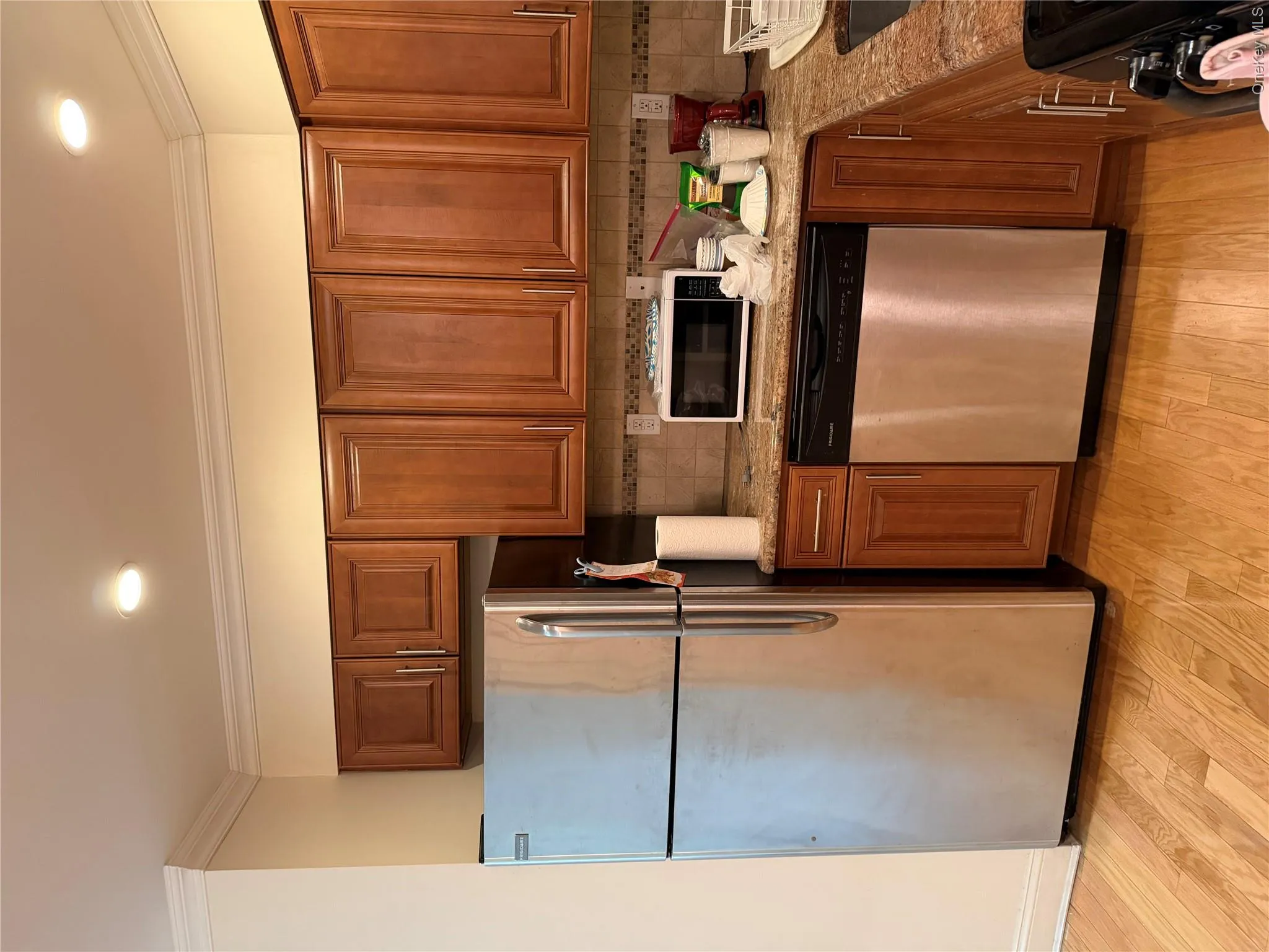 Kitchen featuring wood-finish flooring, recessed lighting, crown molding, stainless steel appliances, and wood cabinetry Kitchen featuring wood-finish flooring, recessed lighting, crown molding, stainless steel appliances, and wood cabinetry