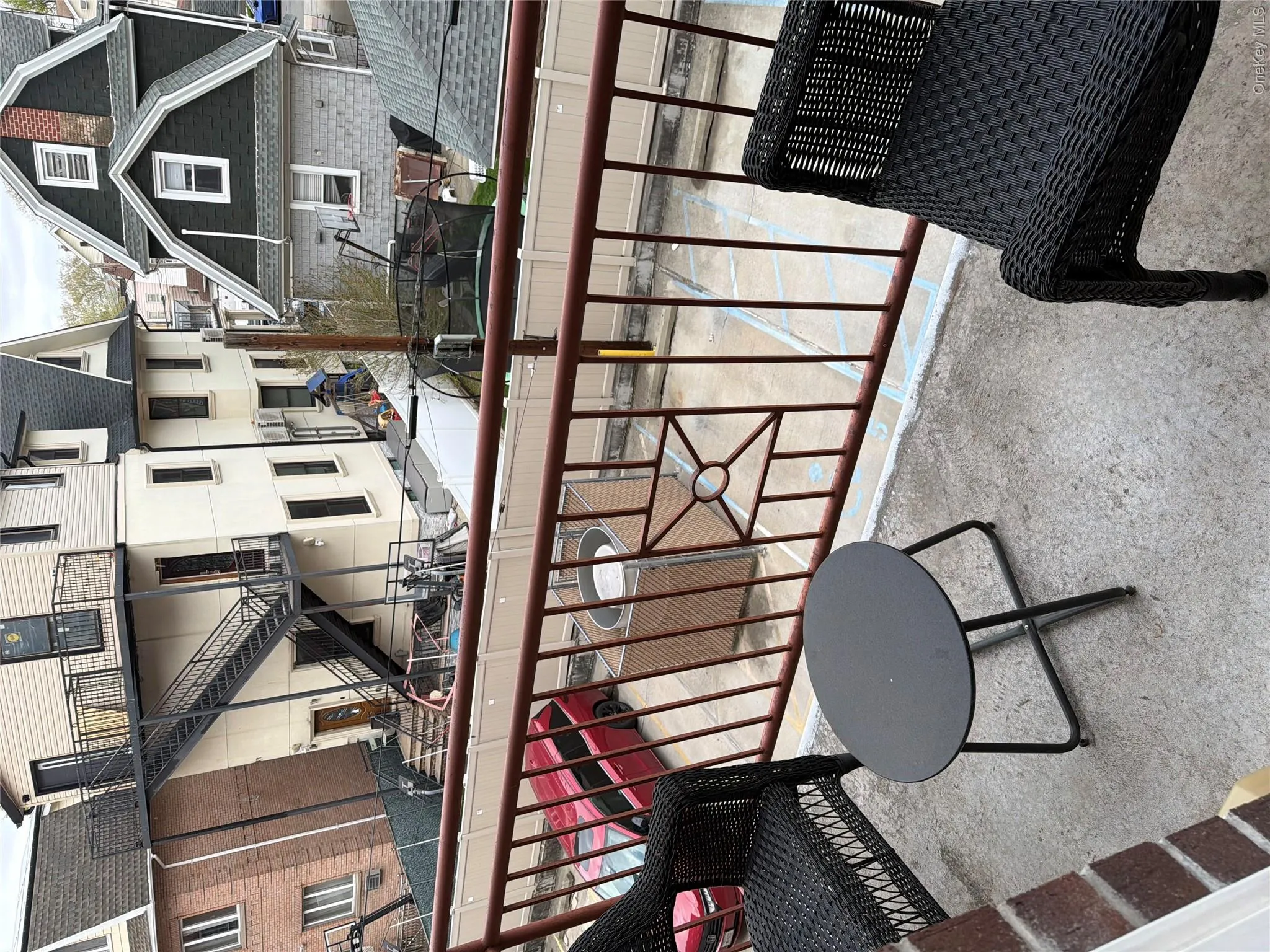 Balcony featuring a decorative metal railing, concrete flooring, and a partial brick wall Balcony featuring a decorative metal railing, concrete flooring, and a partial brick wall