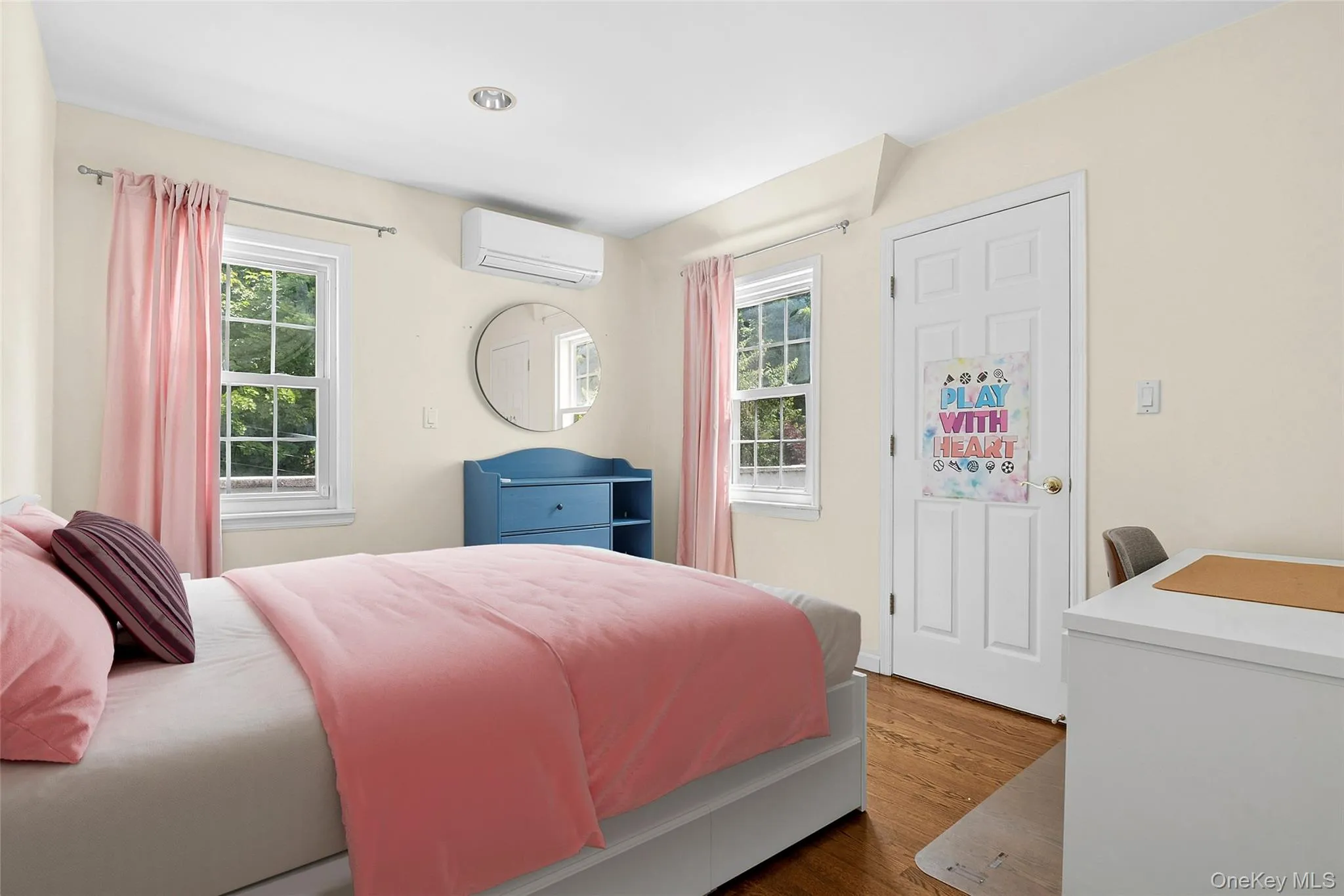 Virtually Staged Bedroom One. Hardwood flooring throughout featuring two double-hung windows, recessed lighting, and a wall-mounted mini-split HVAC unit Virtually Staged Bedroom One. Hardwood flooring throughout featuring two double-hung windows, recessed lighting, and a wall-mounted mini-split HVAC unit